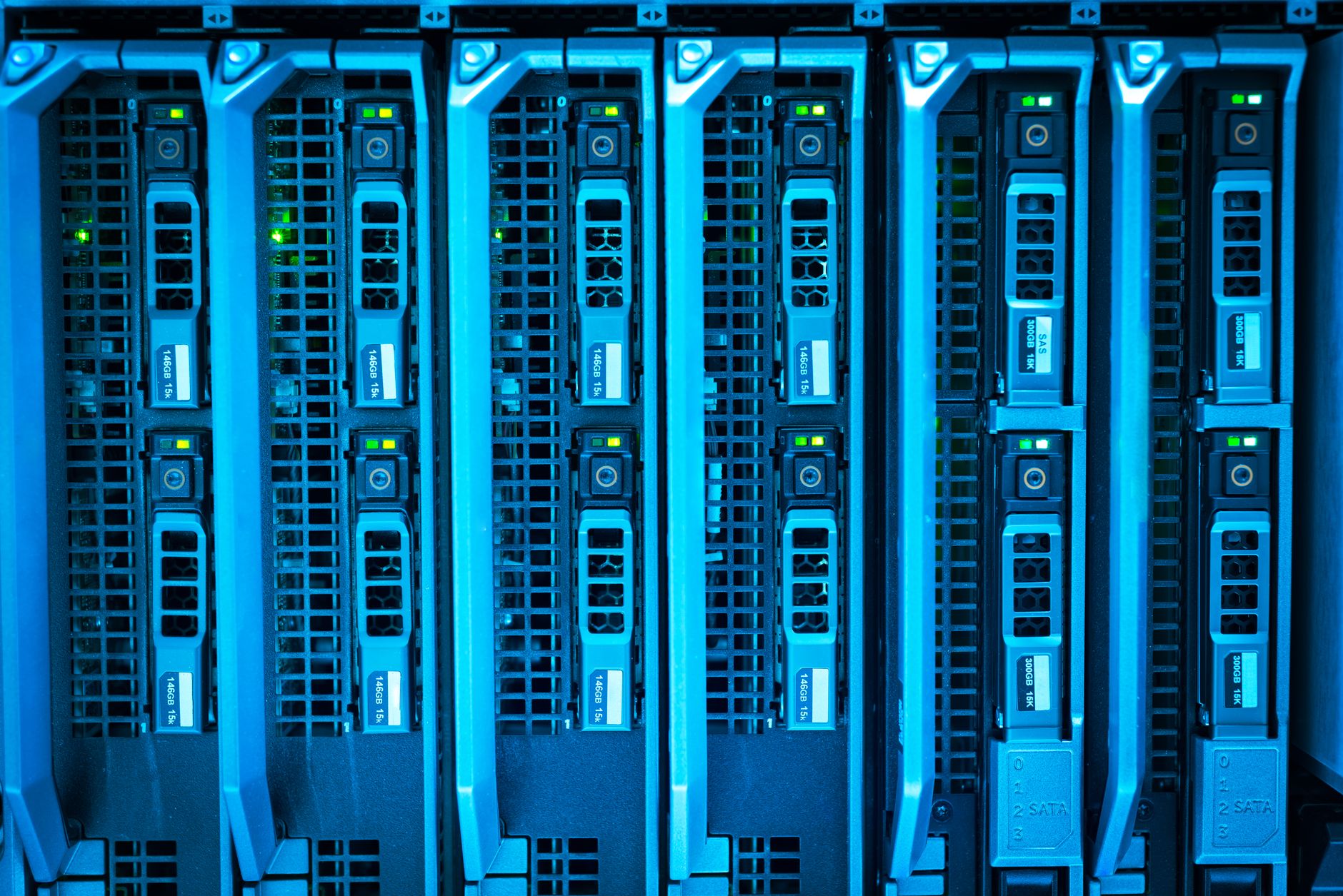 rows of server racks and electronic systems inside a modern defense-technology research facility, with mounted displays showing network architecture diagrams