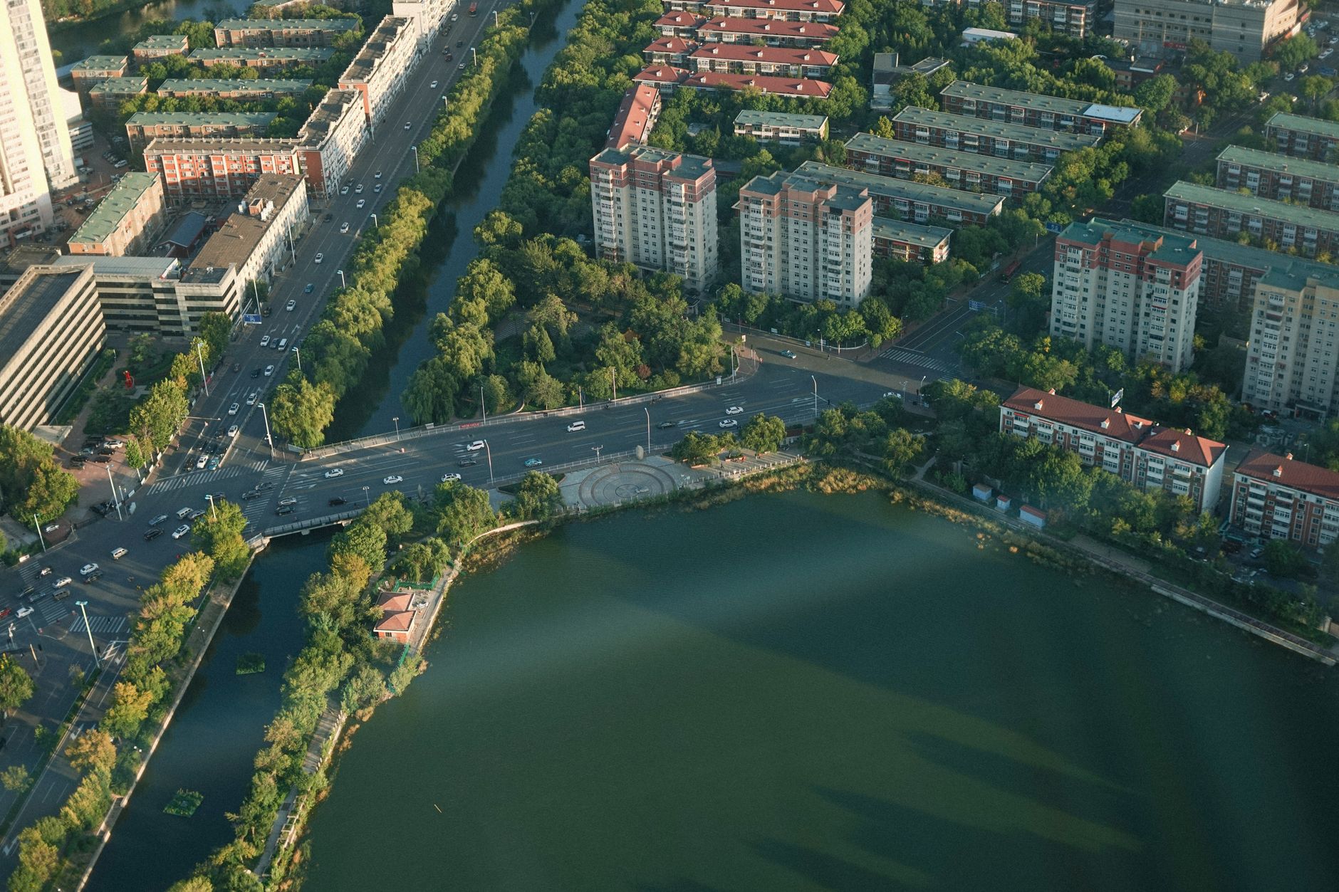 aerial view of a low-rise urban neighborhood along a wide river, damaged rooftops visible, no people in frame