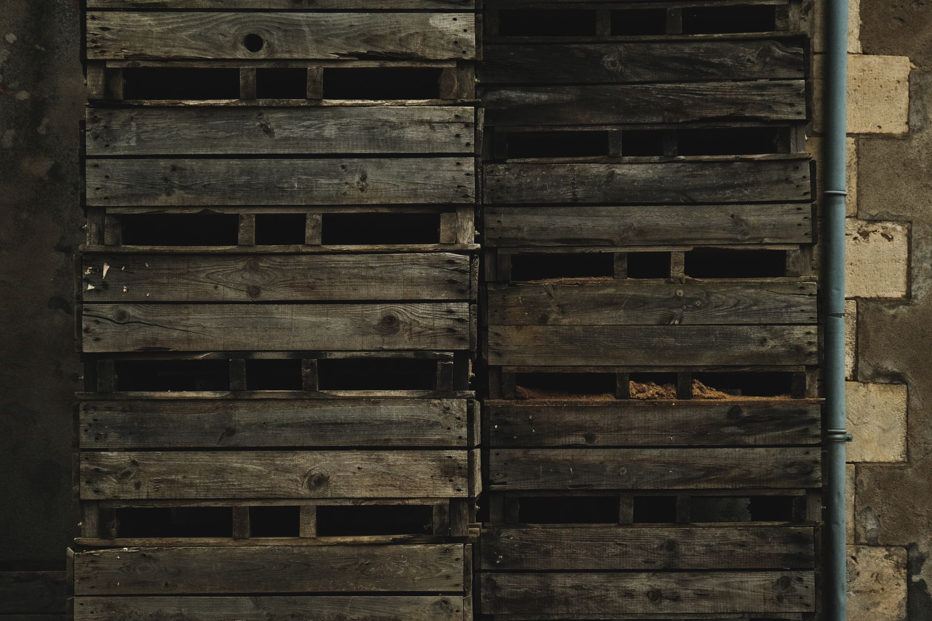 rows of artillery shells and munitions crates stacked inside a large military warehouse facility, with identification markings visible on wooden crates
