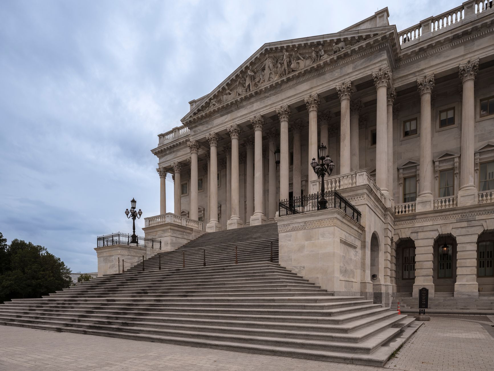 a wide-angle view of a federal government campus in Washington D.C. with perimeter fencing and institutional buildings visible, overcast sky, no individuals as focal point