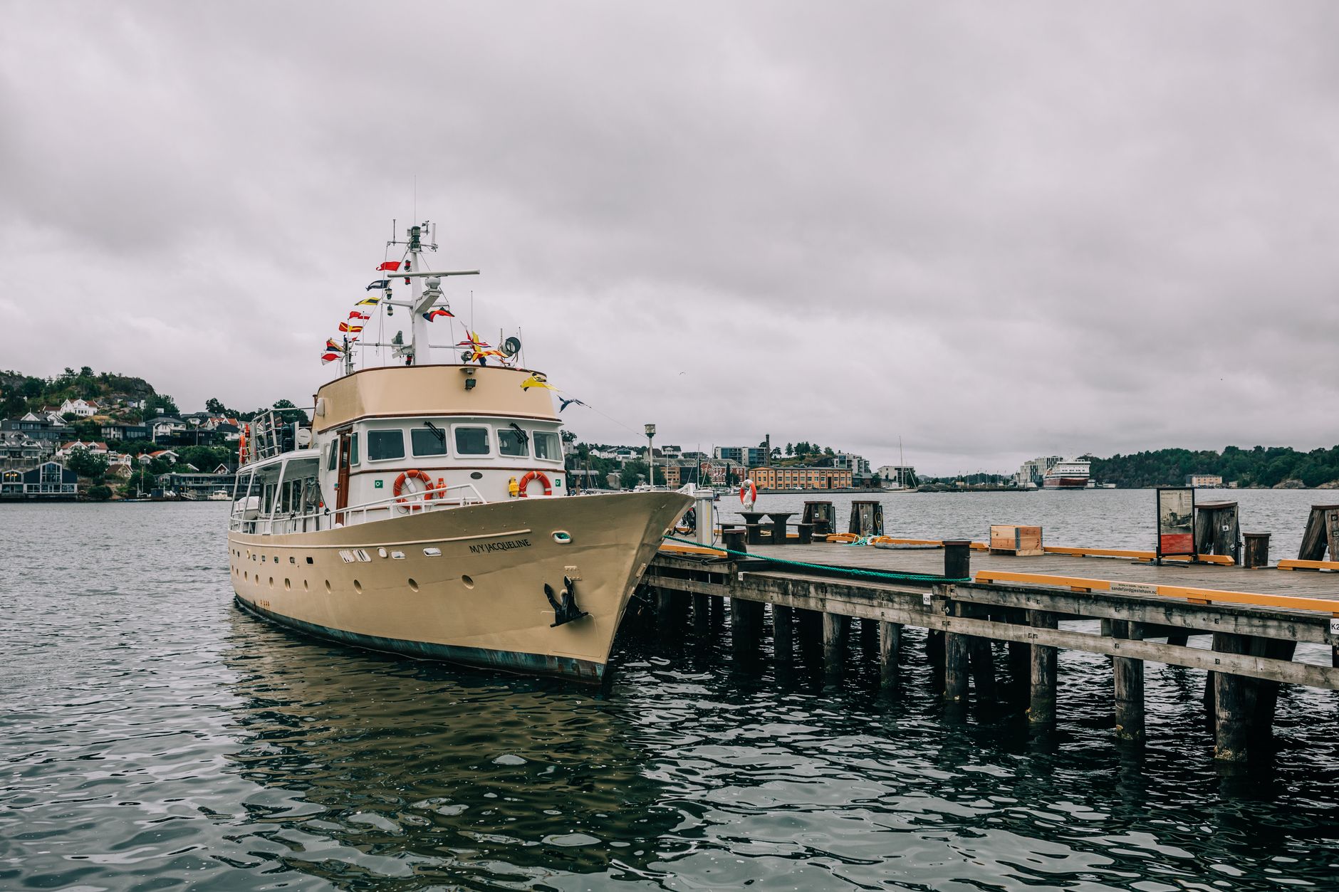 a Navy destroyer moored at a gray waterfront pier during overcast conditions, lines secured and gangway visible, no personnel as focal point