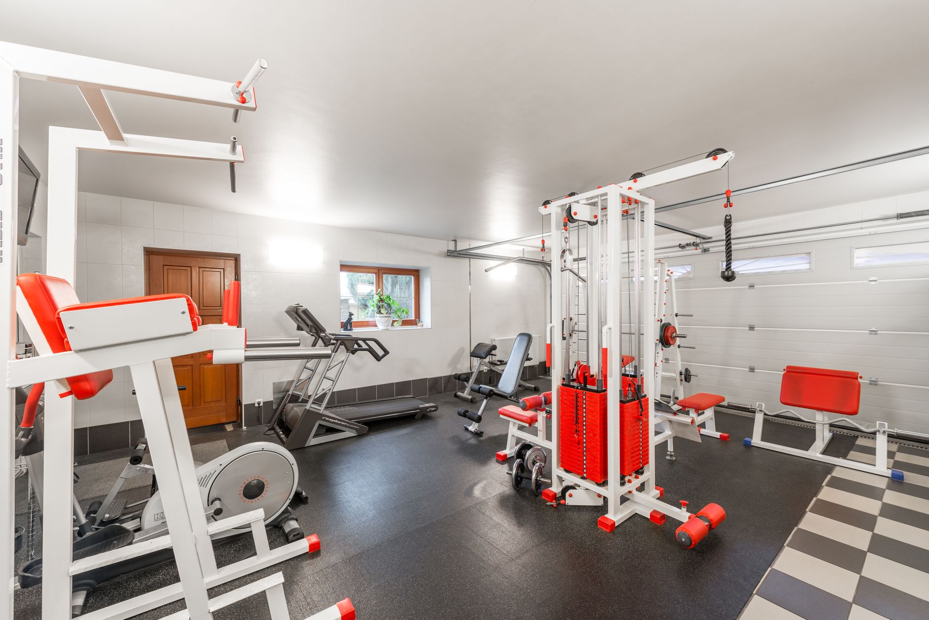 a wide shot of an NFL-style weight room and equipment area inside a team training facility, with blocking dummies and agility ladders arranged along the sideline, no people as focal point