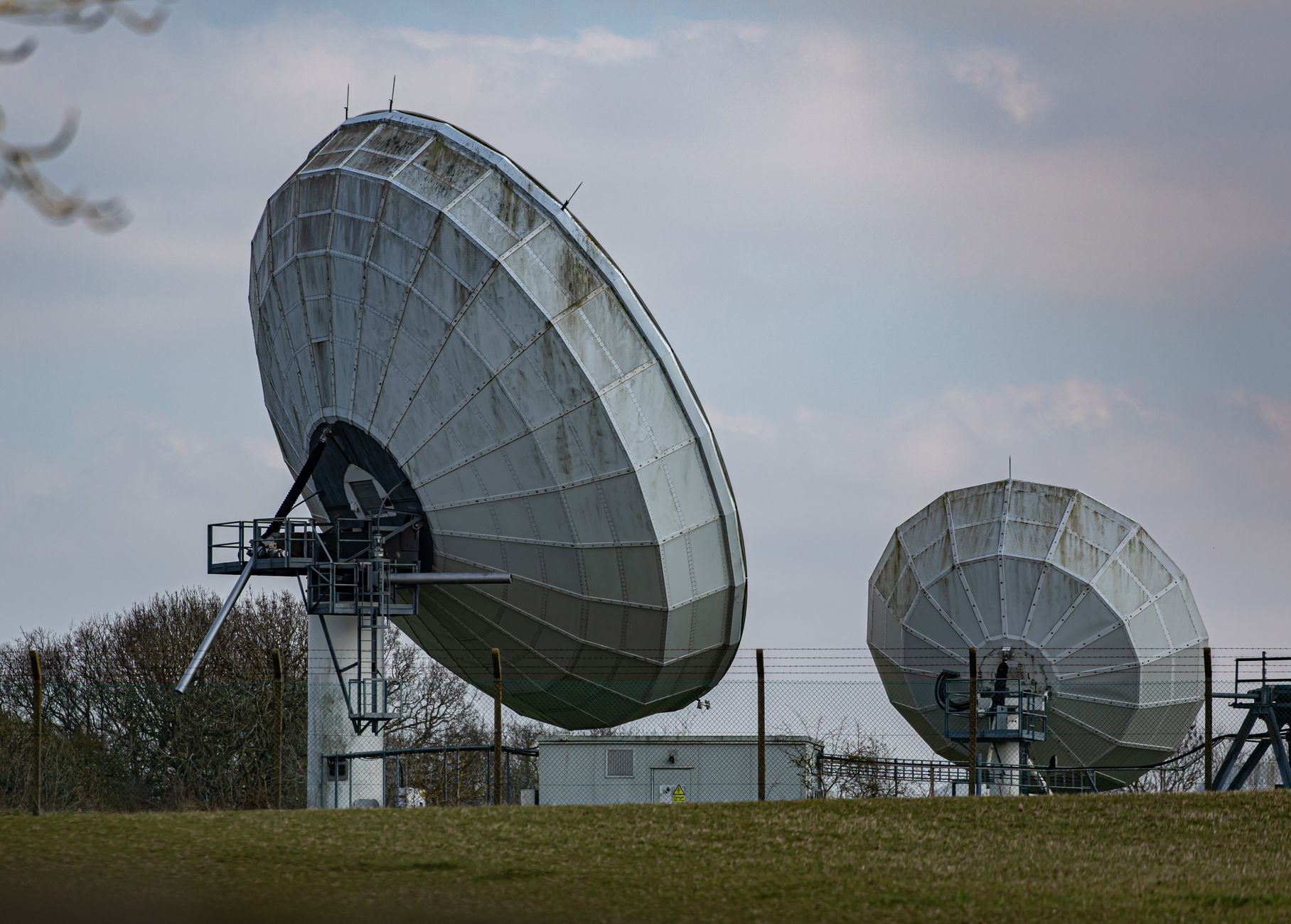 a portable counter-drone detection and jamming system deployed on open terrain near a perimeter fence at a U.S. military installation, equipment racks and antenna arrays visible in the foreground