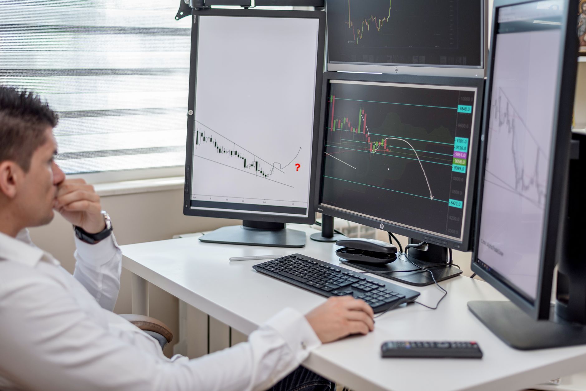 a large monitor array in a financial trading operations center displaying real-time market data and contract resolution charts, with no identifiable faces visible