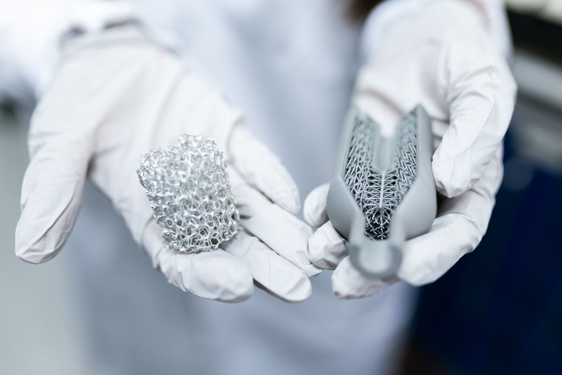rows of gray polymer and metal 3D-printed mechanical components laid out on a metal table in a well-lit forward maintenance facility, no people as focal point