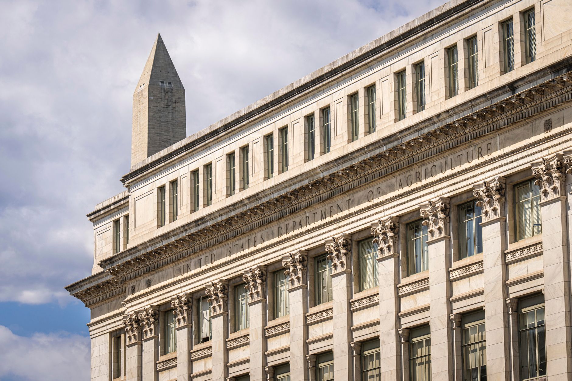 exterior view of a classical government building facade in Washington D.C., stone columns and wide steps under overcast sky, no people in foreground