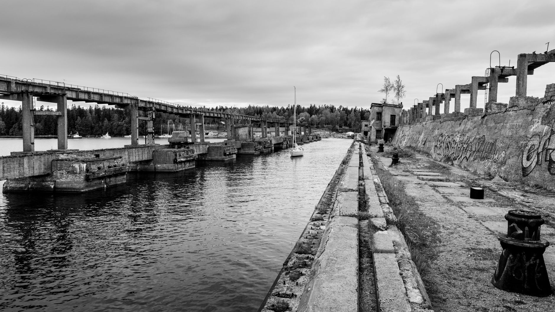 wide aerial view of a northern Russian naval submarine base showing large submarines moored at concrete piers with visible netting structures draped over and around the hulls