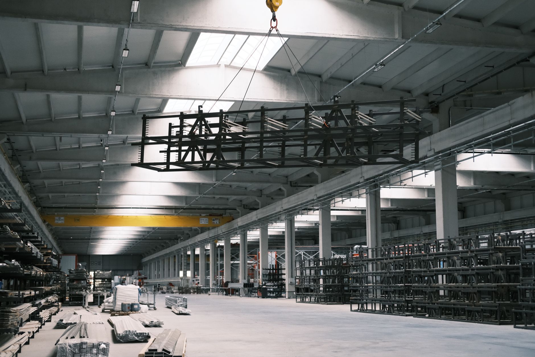 the interior of a large Russian submarine assembly hall at Sevmash, with a partially outfitted submarine hull on blocks surrounded by scaffolding, equipment, and overhead lighting in an industrial setting
