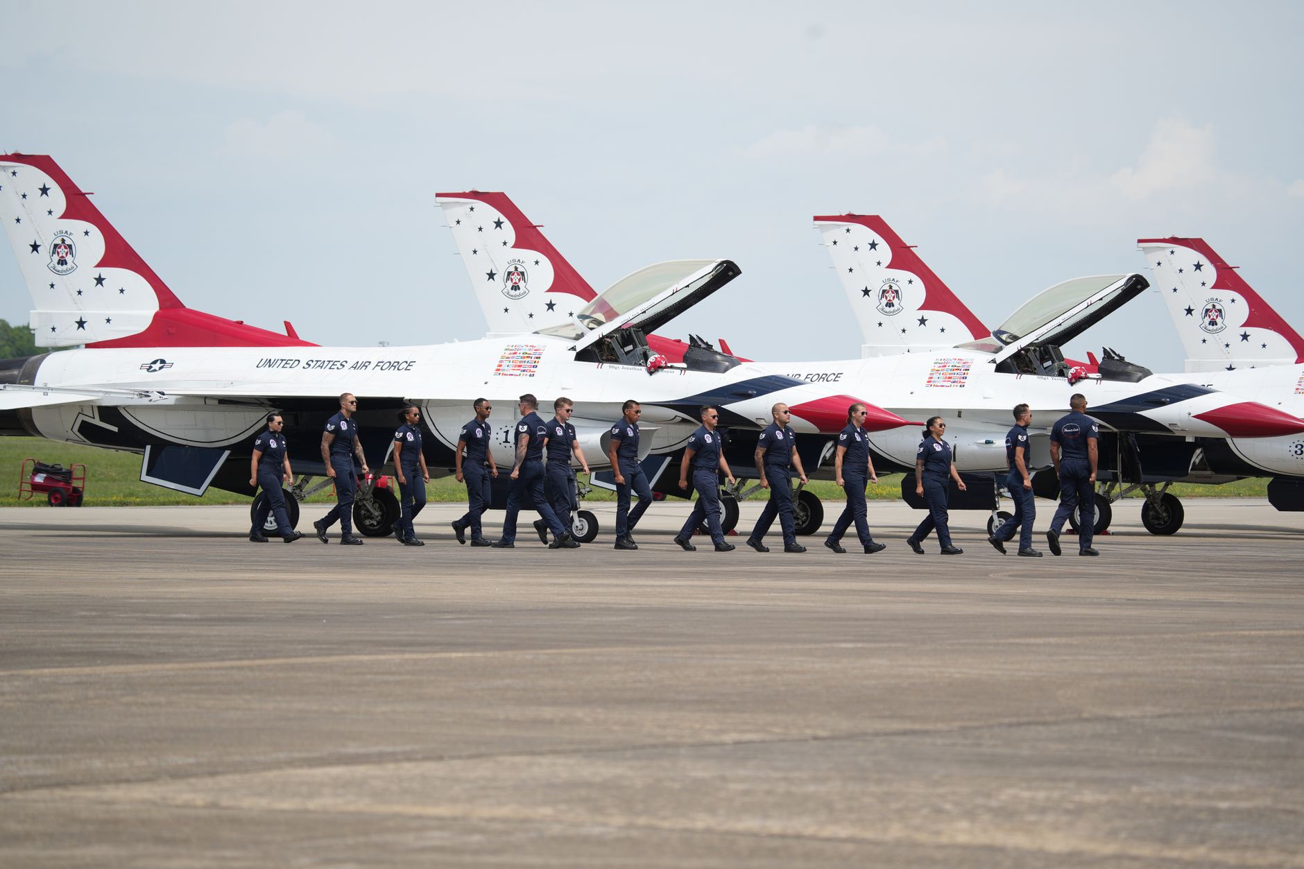 a flight line at Osan Air Base showing parked F-16 Fighting Falcons under grey overcast skies, viewed from a wide angle with ground support equipment visible