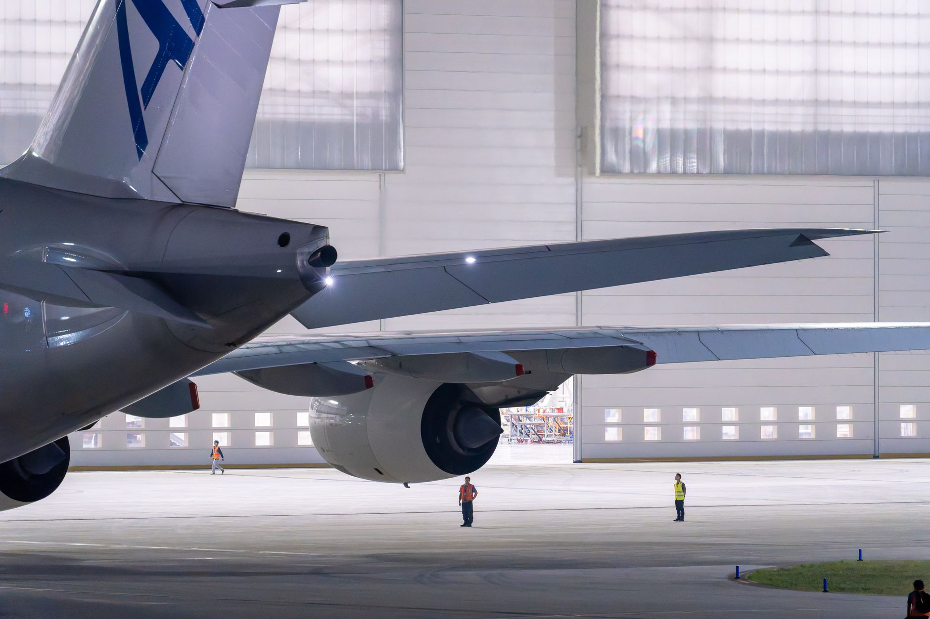 a U.S. Air Force surveillance aircraft parked on a tropical tarmac at a forward operating location, ground crew visible in the background near a hangar