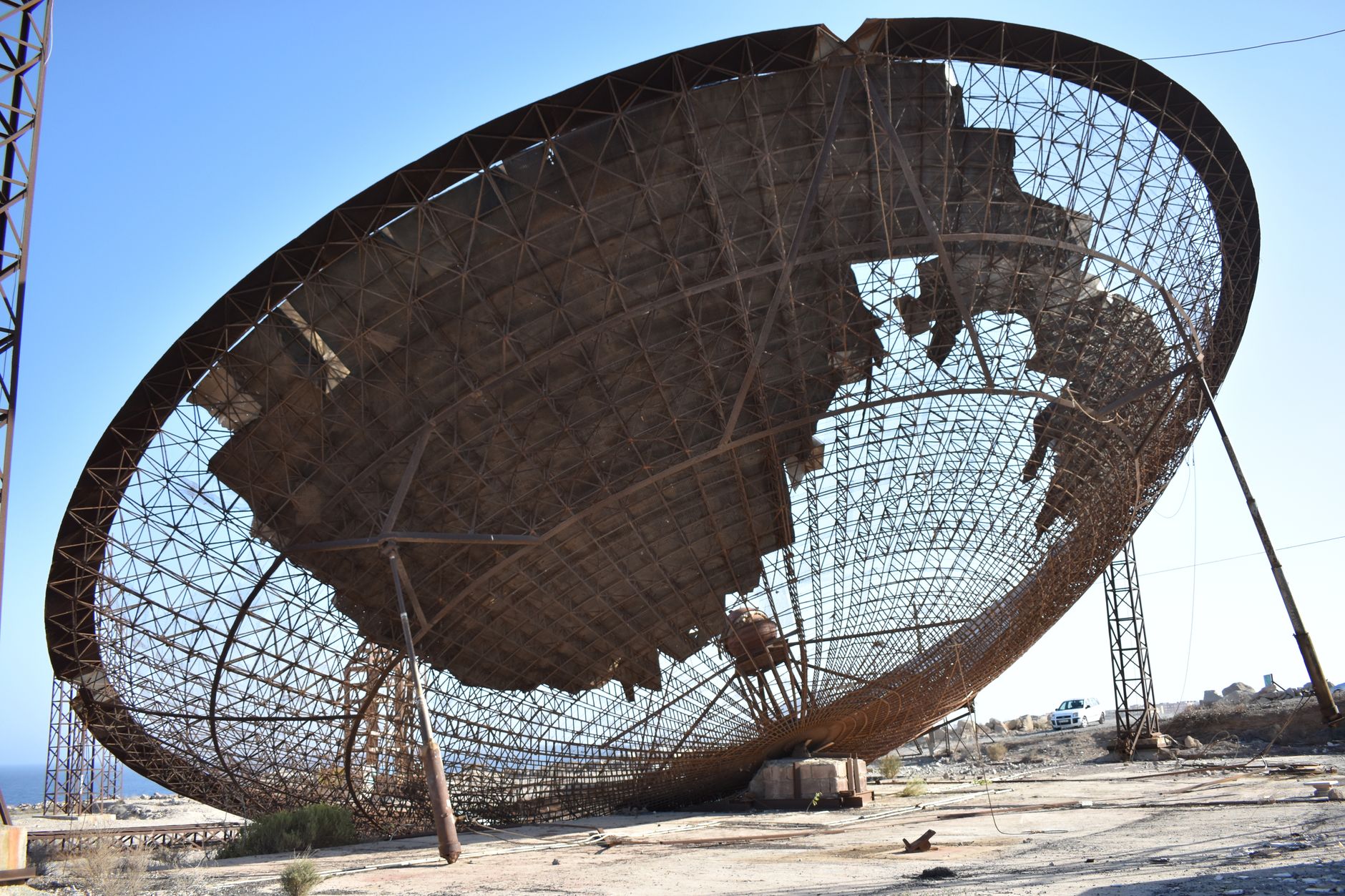 a satellite ground station with large dish antennas pointed skyward in an open desert facility, late afternoon light
