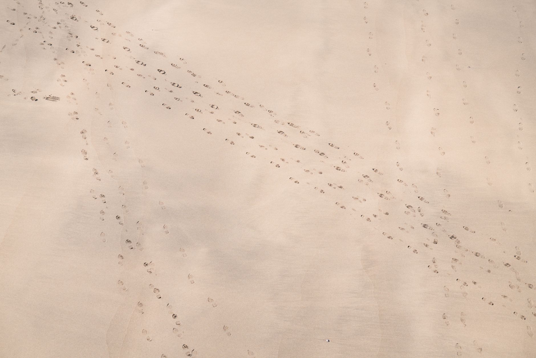 aerial view of a remote desert military installation with perimeter fencing and vehicle tracks visible across sandy terrain