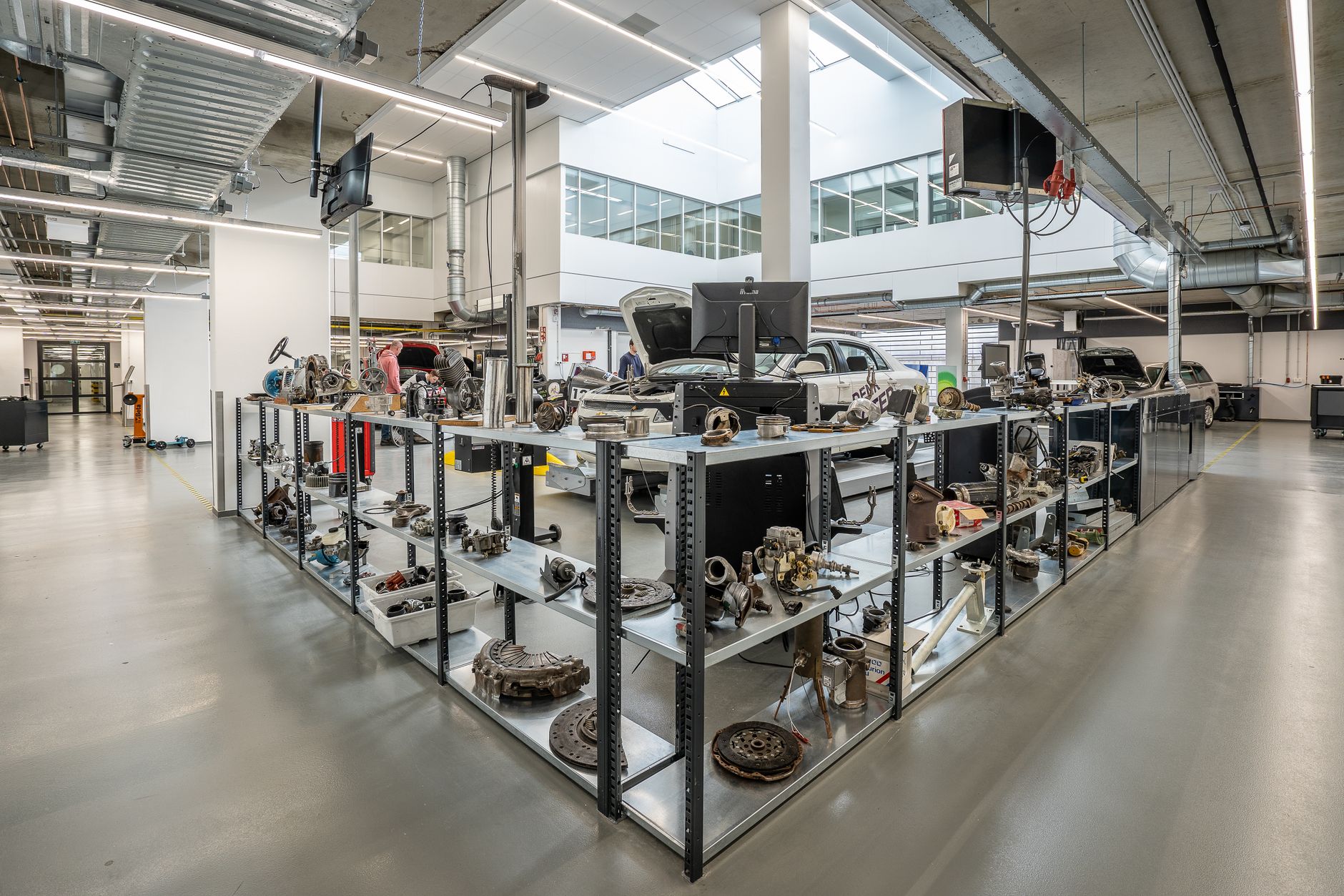 a vehicle depot production line showing partially disassembled tracked military vehicles on maintenance stands, with tooling and parts staged along the floor