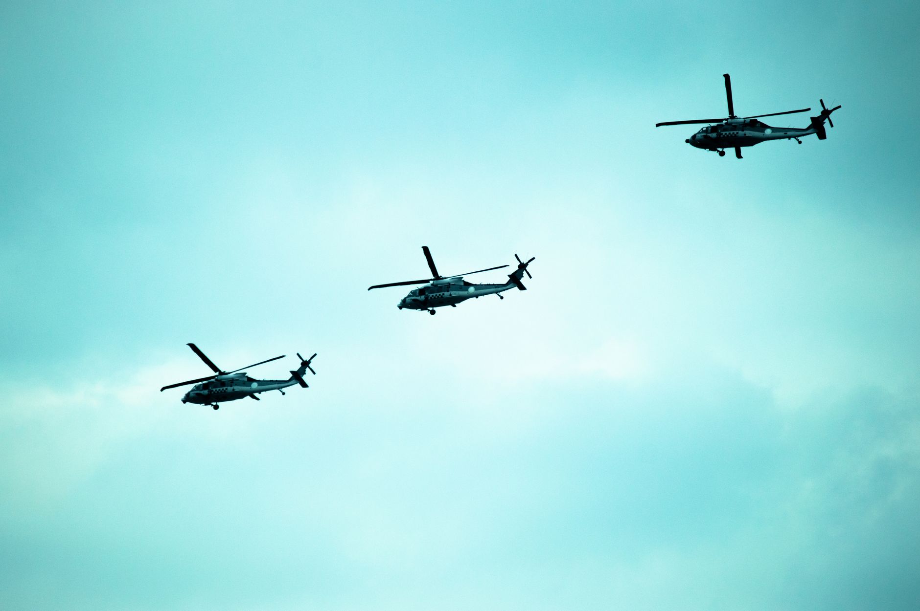 a UH-60 Black Hawk helicopter hovering low over a Taiwanese military training range, surrounded by hilly terrain and light ground mist