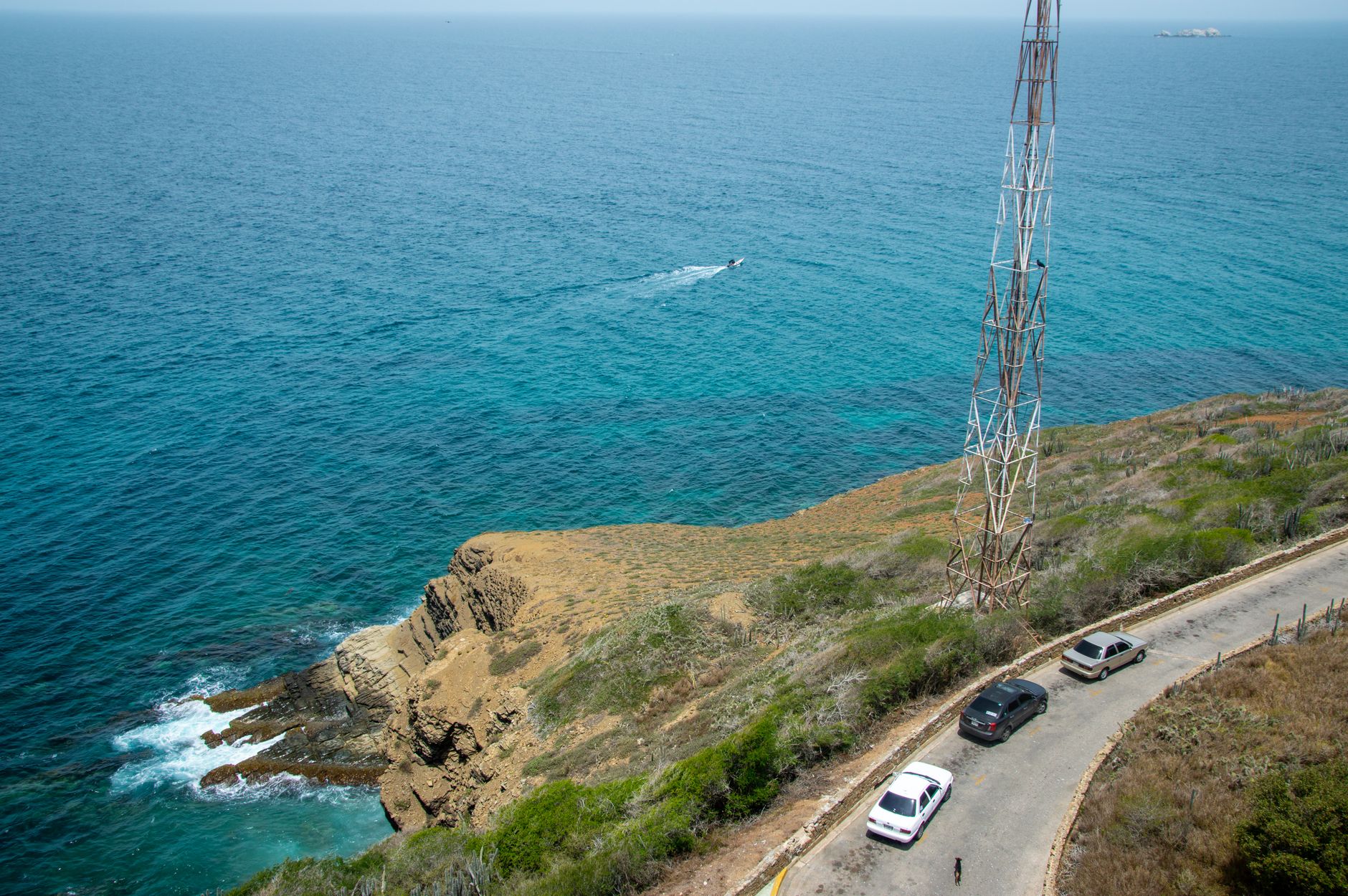 a ground-based Harpoon coastal defense launcher on an open coastal test range, with the ocean visible in the background and support vehicles positioned nearby