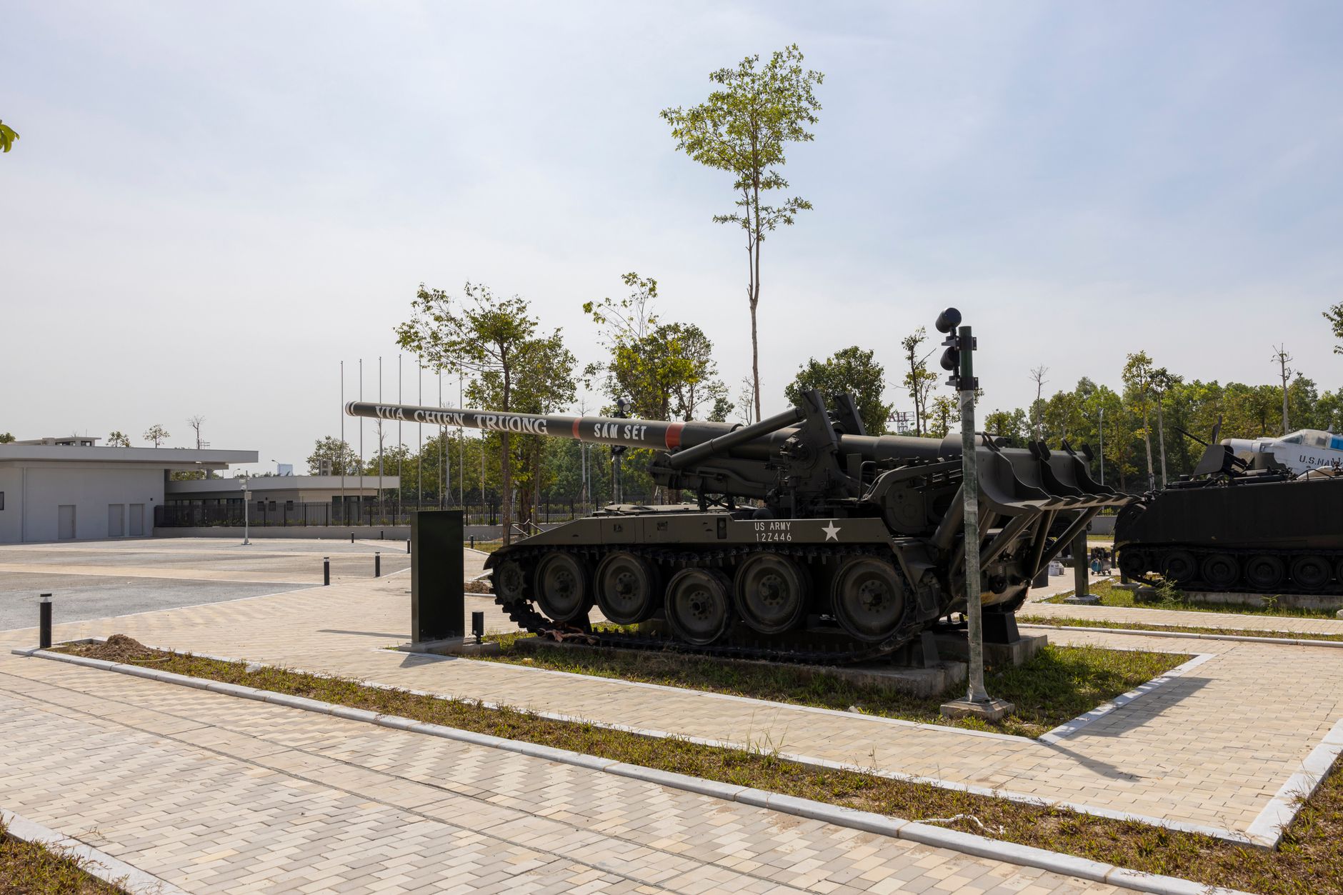 rows of M1A2 Abrams tanks parked inside a large military vehicle depot, viewed from a wide angle showing their distinctive angular turrets and reactive armor arrays