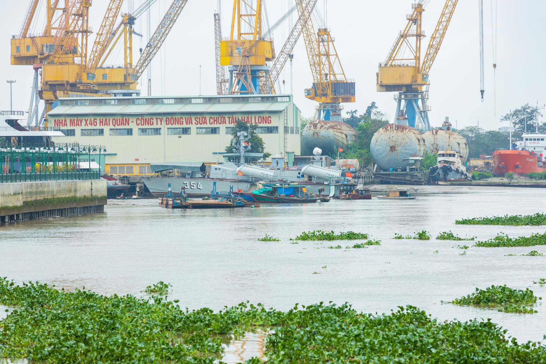 aerial view of a Taiwanese naval vessel docked at a harbor facility with port infrastructure and cranes in the background