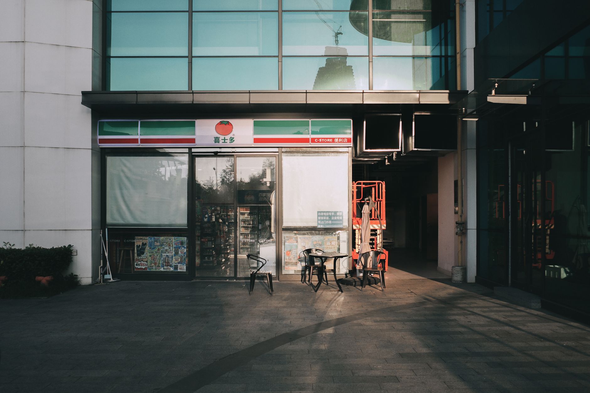 a military command post set up inside a ground-floor commercial space, with maps spread on tables and communication equipment arranged near large storefront windows overlooking a city street