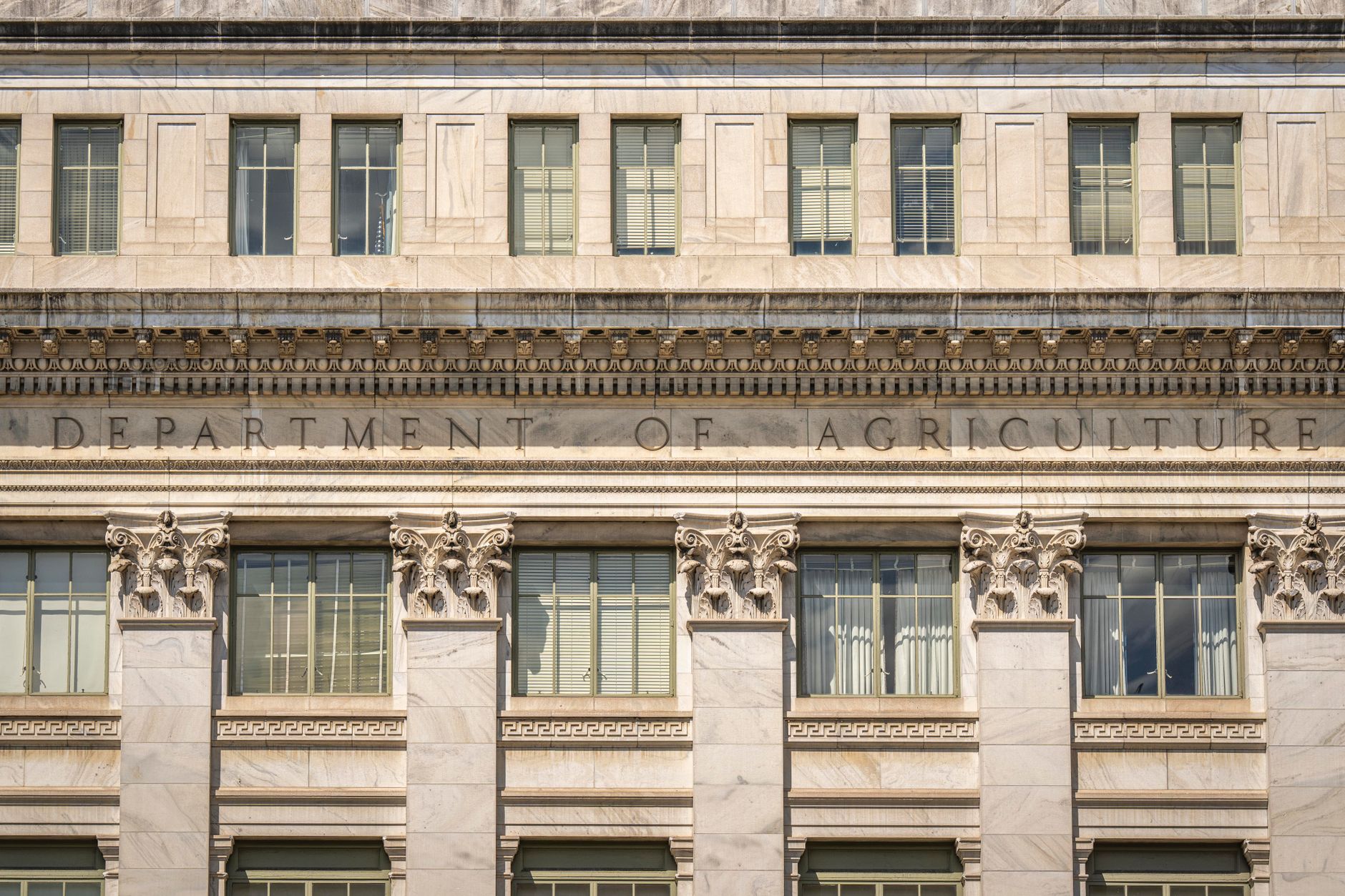 exterior of the Robert F. Kennedy Department of Justice building in Washington D.C., wide-angle view of the neoclassical stone facade and main entrance on a clear day