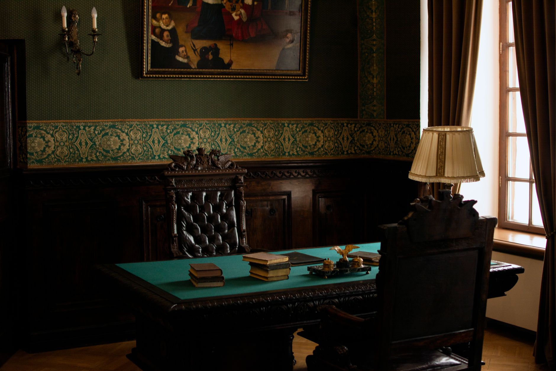 an ornate executive office interior featuring gold-toned curtains, a large wooden desk, and formal architectural detailing, viewed from across the room