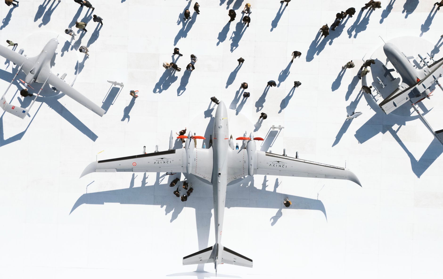 interior of a large defense exhibition hall with military helicopters on static display, crowds of uniformed attendees visible in the background