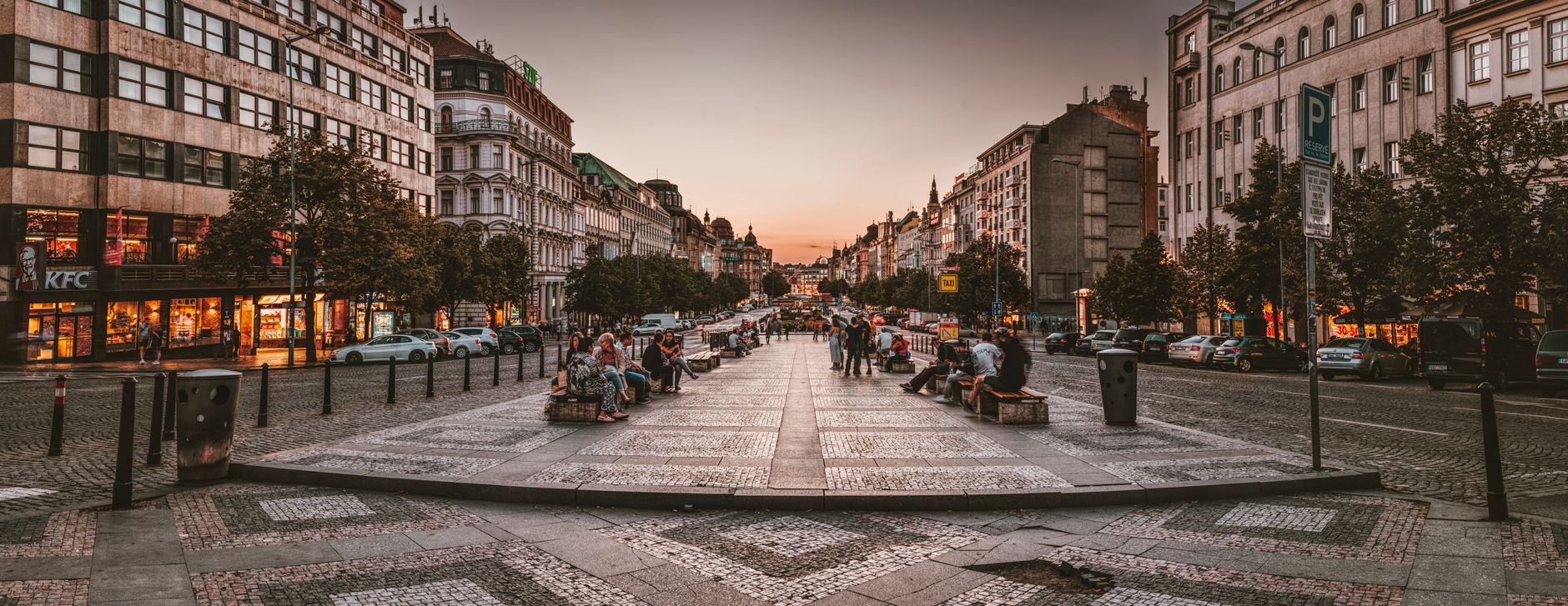 a wide shot of an empty central urban square in a European city, cobblestones visible under overcast sky, protest banners draped across railings in the distance, no people in foreground
