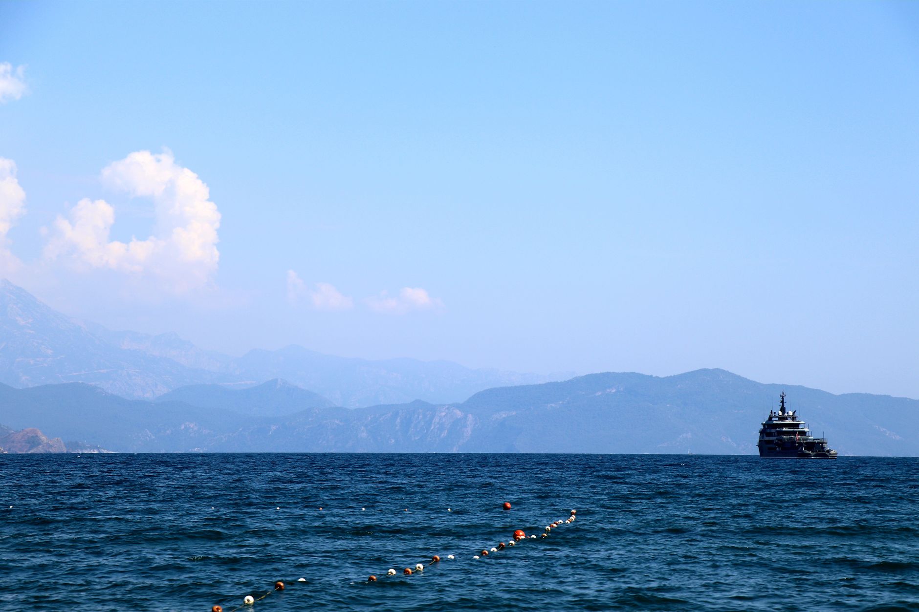a US Navy guided-missile destroyer underway in open blue water, viewed from a trailing vessel at distance, with no landmass visible