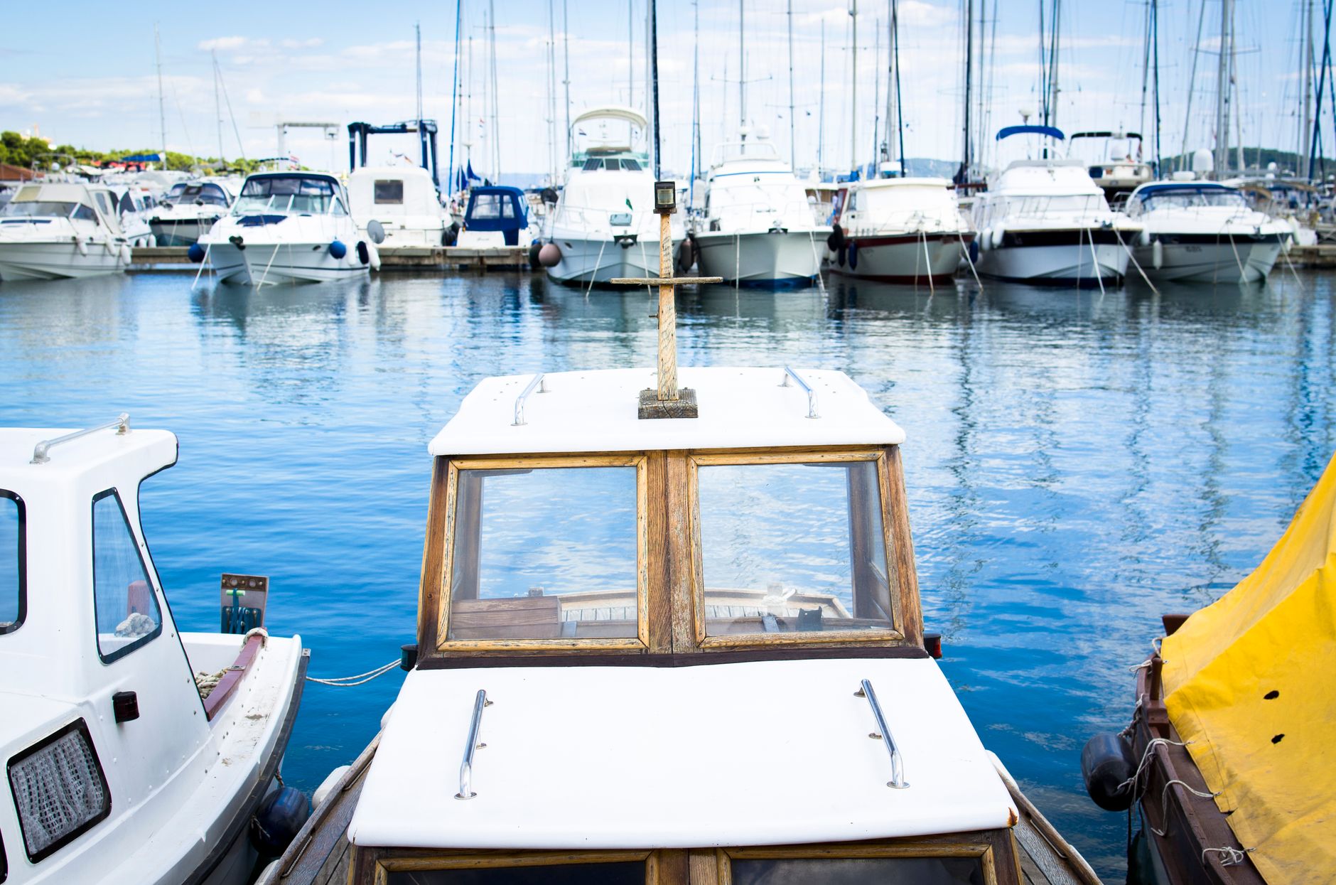 a small military watercraft moored at a dock alongside a larger amphibious vessel, viewed from a pier-level angle with open water in the background