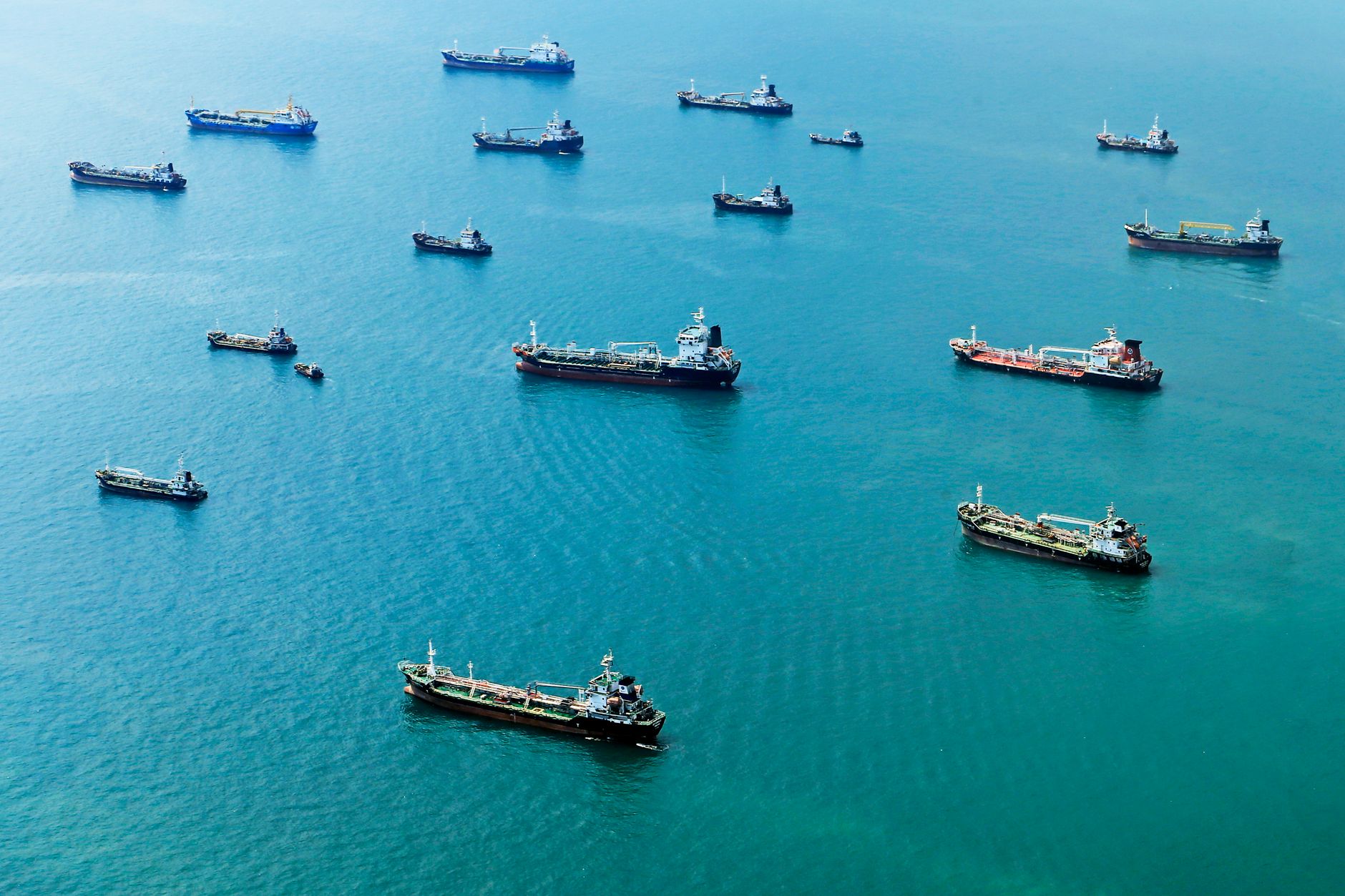 a Navy replenishment-at-sea evolution with a supply vessel alongside a carrier, fuel lines and cargo transfers visible between the two ships
