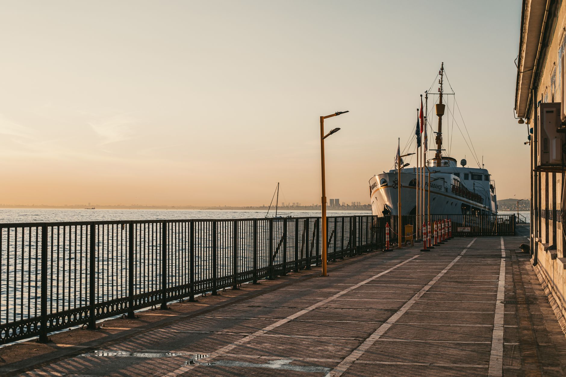 a naval pier with mooring lines and shore-side family waiting area, empty of ships, late afternoon light