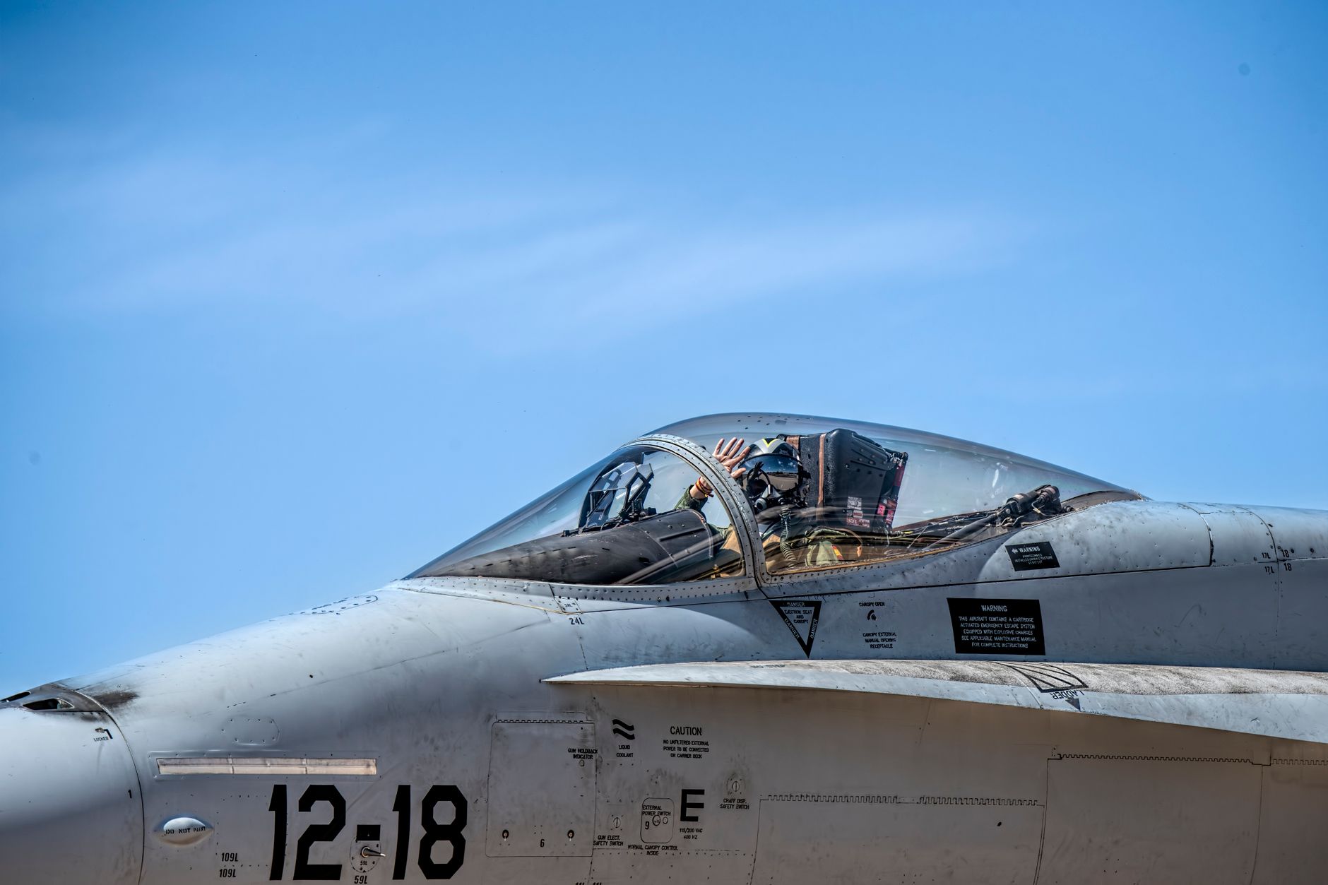 the flight deck of a Nimitz-class aircraft carrier at sea, with aircraft positioned on the deck and the ocean extending to the horizon under clear skies