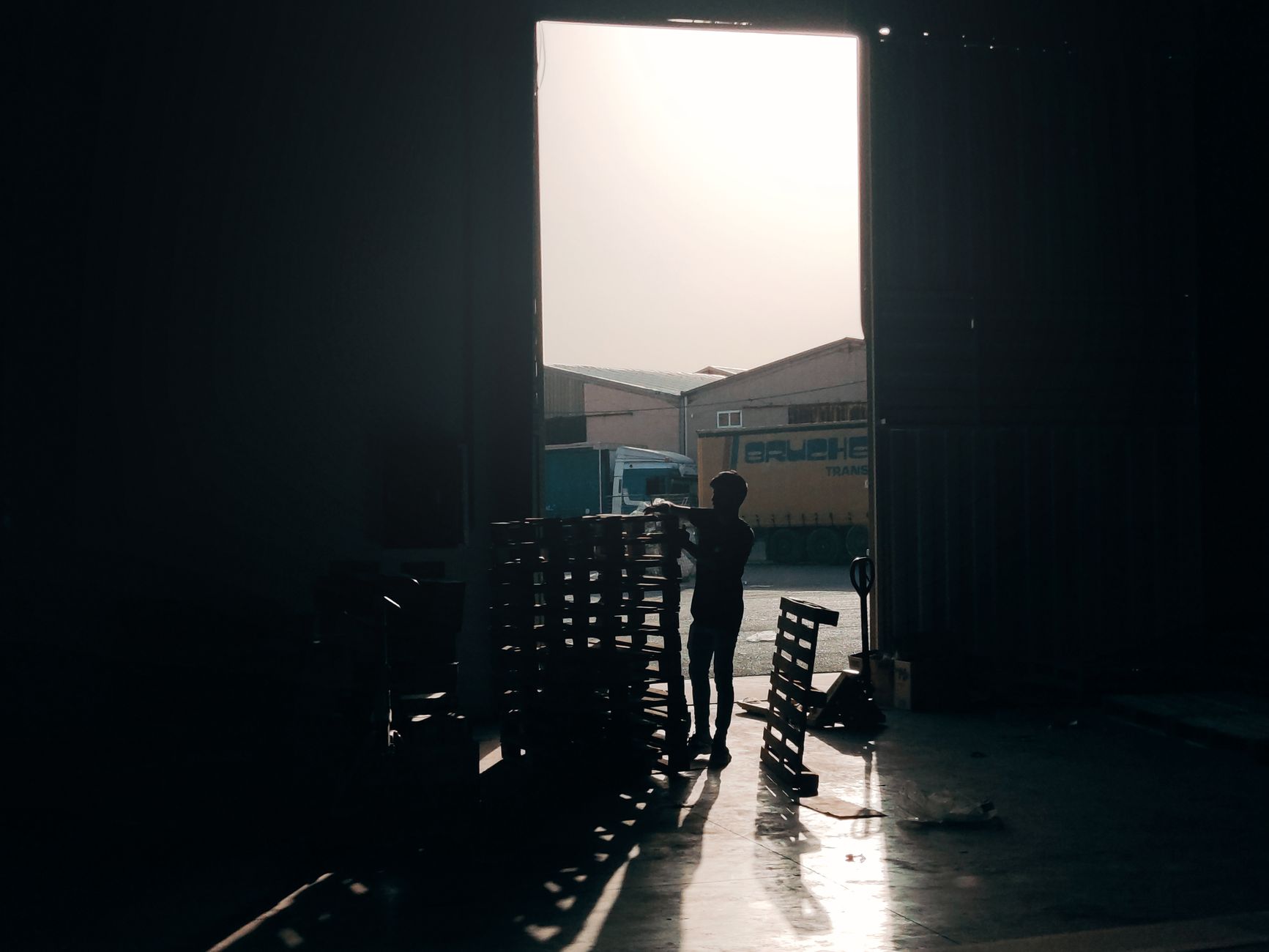 a NATO logistics facility interior with palletized equipment cases stacked near loading bays, overhead industrial lighting, no personnel as focal point