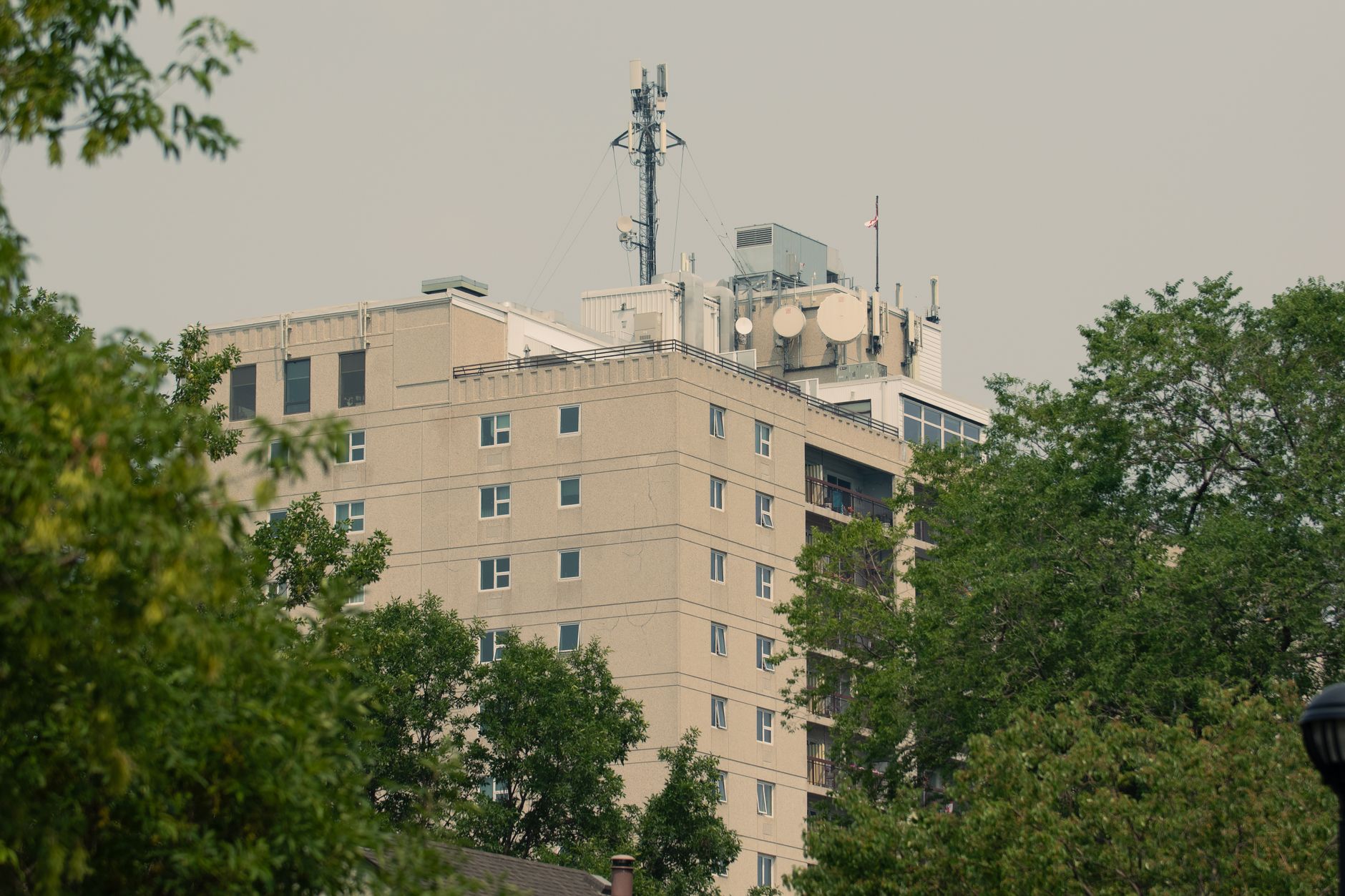 exterior of a cybersecurity firm's headquarters building with visible satellite uplink equipment and secure facility signage, wide environmental shot