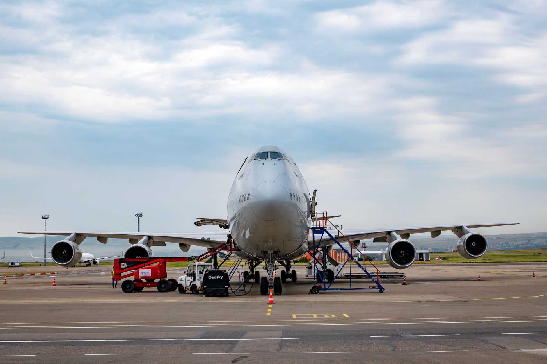 an MQ-9 Reaper drone parked on a tarmac at a desert air base, maintenance equipment visible nearby, wide environmental shot
