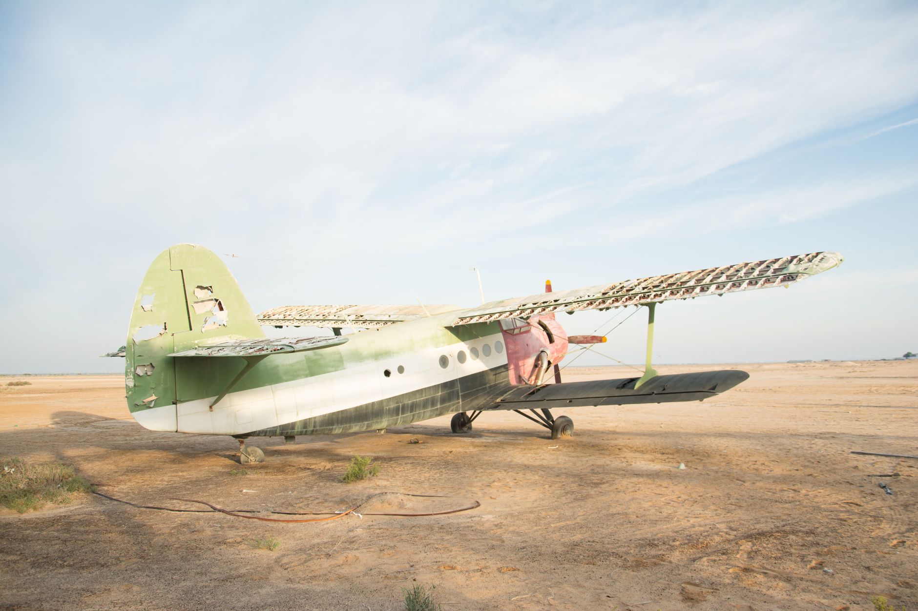 a hardened aircraft shelter on a U.S. forward air base in a desert environment, blast doors partially open, taxiway visible in foreground