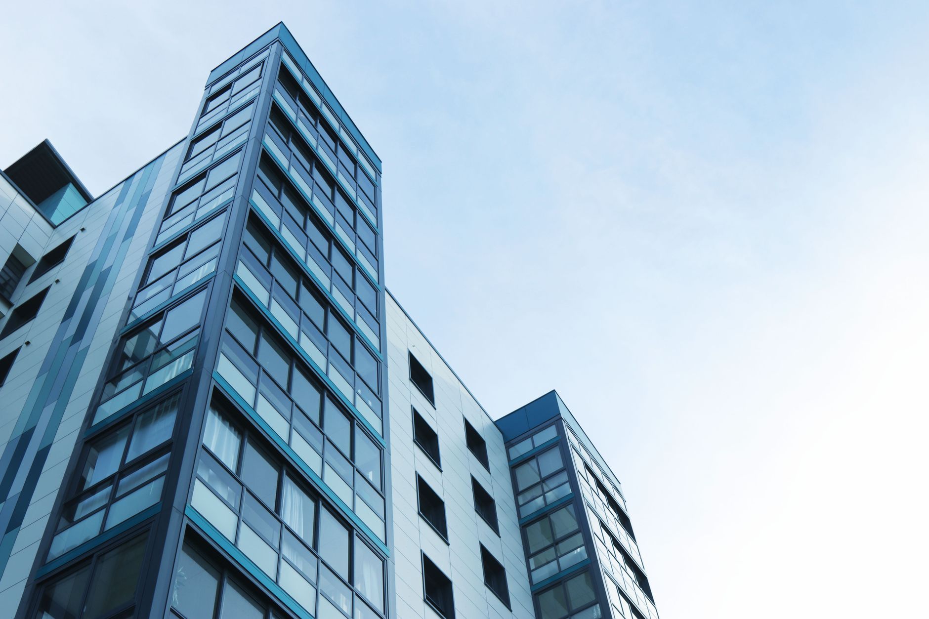 a modern glass-facade venture capital office building exterior in a dense urban tech district, midday light, no signage visible
