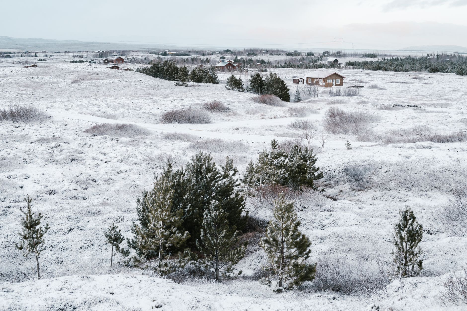 an aging military airfield in a subarctic landscape, with snow-dusted runways and maintenance hangars visible from an elevated angle, no personnel as focal point