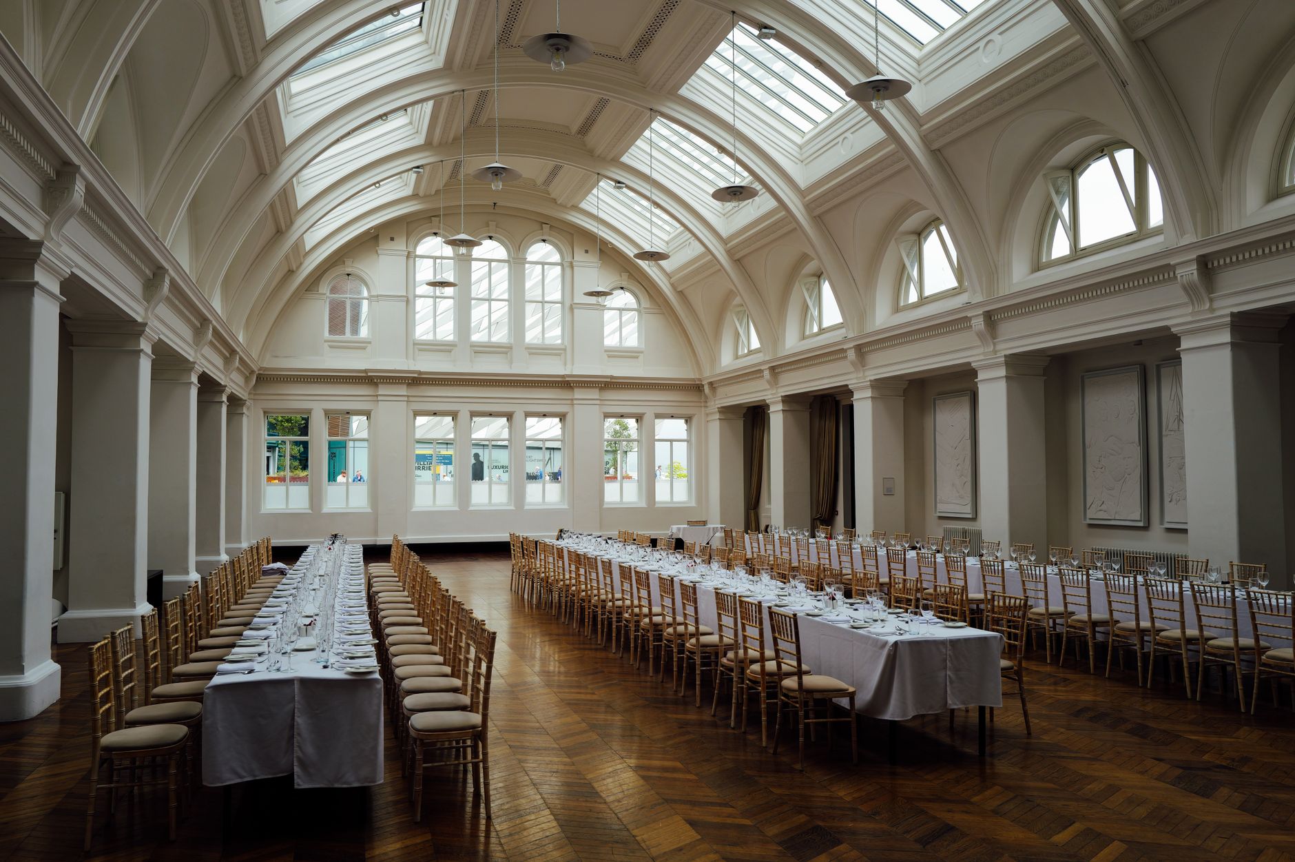 a wide interior shot of a formal state reception hall with ornate chandeliers and rows of empty chairs arranged for an official ceremony, no people in the foreground