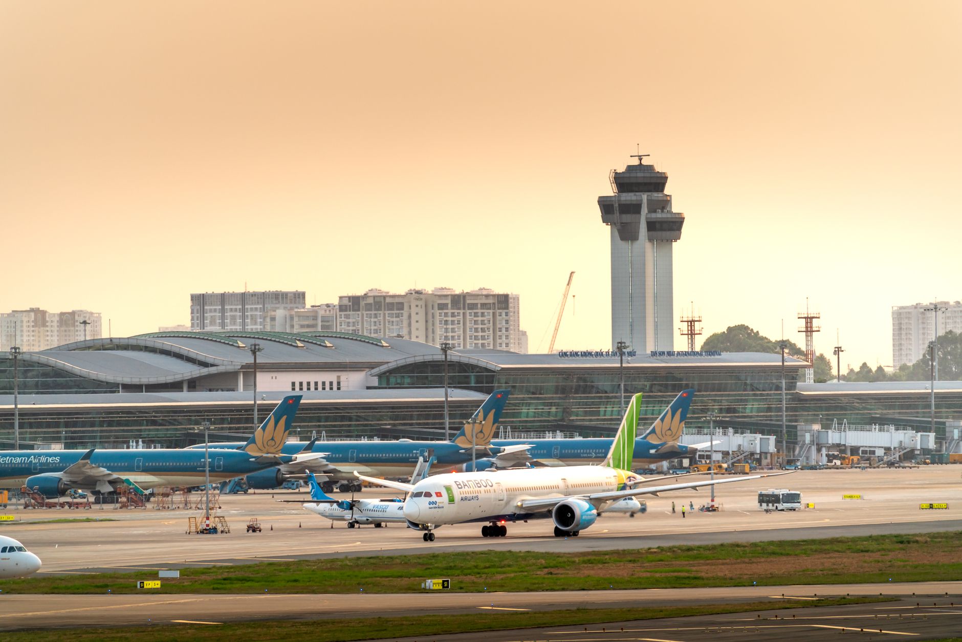 wide-angle view of a large military airfield tarmac with a presidential aircraft silhouette parked near a terminal building at dusk