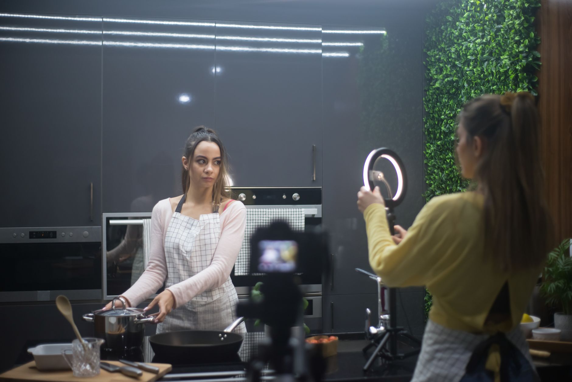 a social media content studio setup with ring lights, a pristine kitchen backdrop, and a tablet displaying analytics, photographed from a wide angle with no identifiable faces