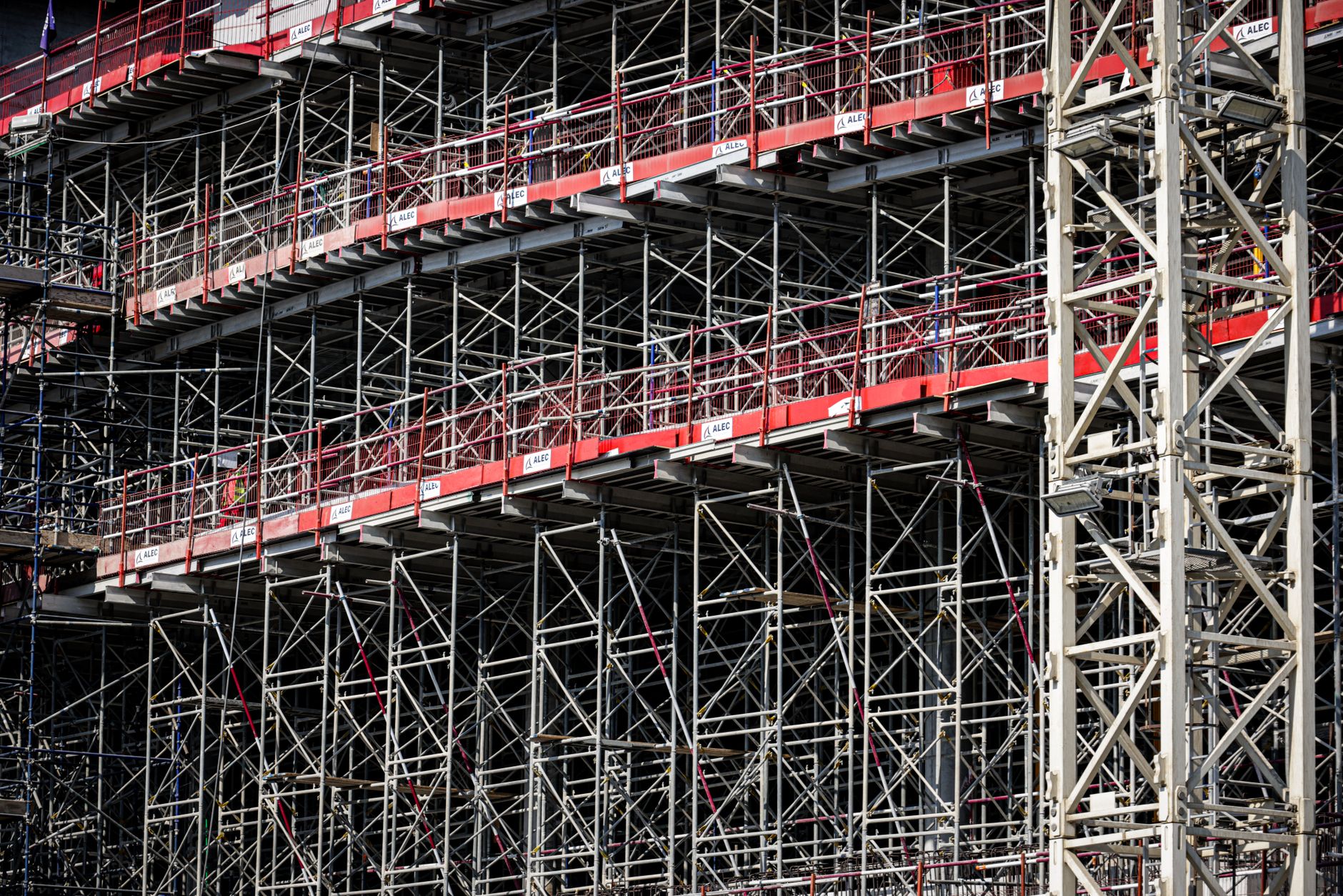 a covered dry dock structure at a coastal shipyard, viewed from above, with support equipment and industrial scaffolding visible around the perimeter