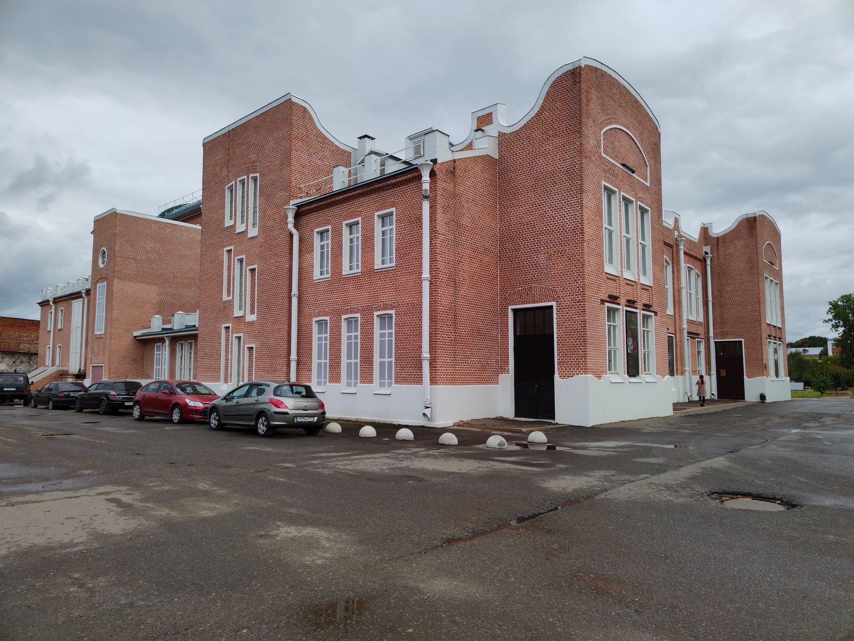 exterior of a National Guard armory building, brick facade with unit signage visible, parking lot in foreground