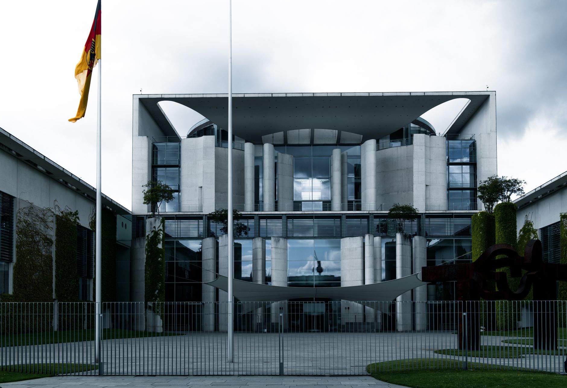 a government security processing facility exterior with badge readers and reinforced entry points visible, photographed from a public vantage point showing the architectural environment