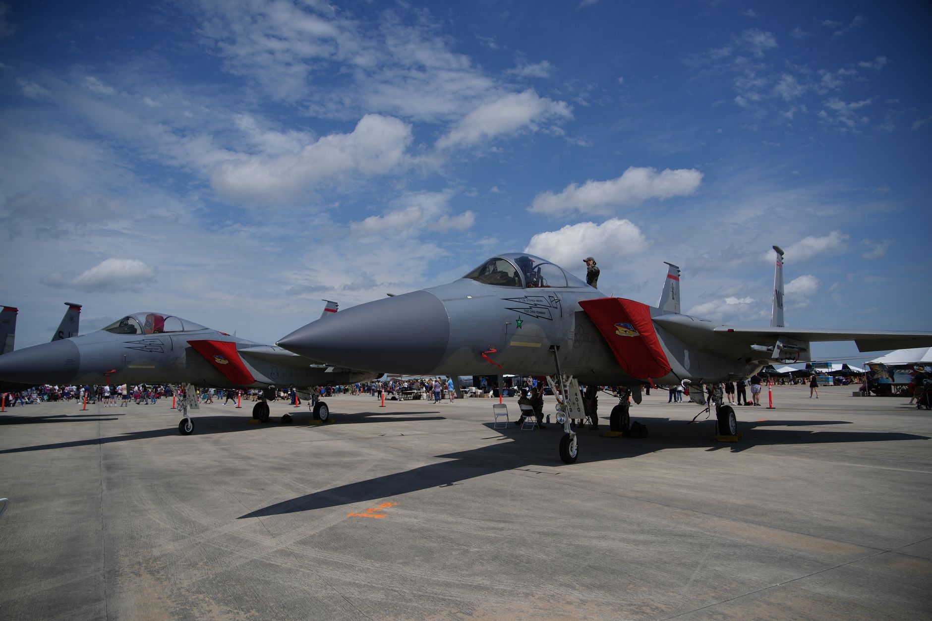 an F-15EX Eagle II fighter jet parked on a flight line at a U.S. Air Force base, ground crew equipment visible nearby, wide environmental shot