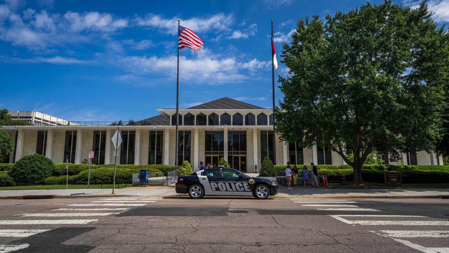 a federal law enforcement field office exterior with government vehicles parked outside, viewed from across a wide parking lot in an urban setting