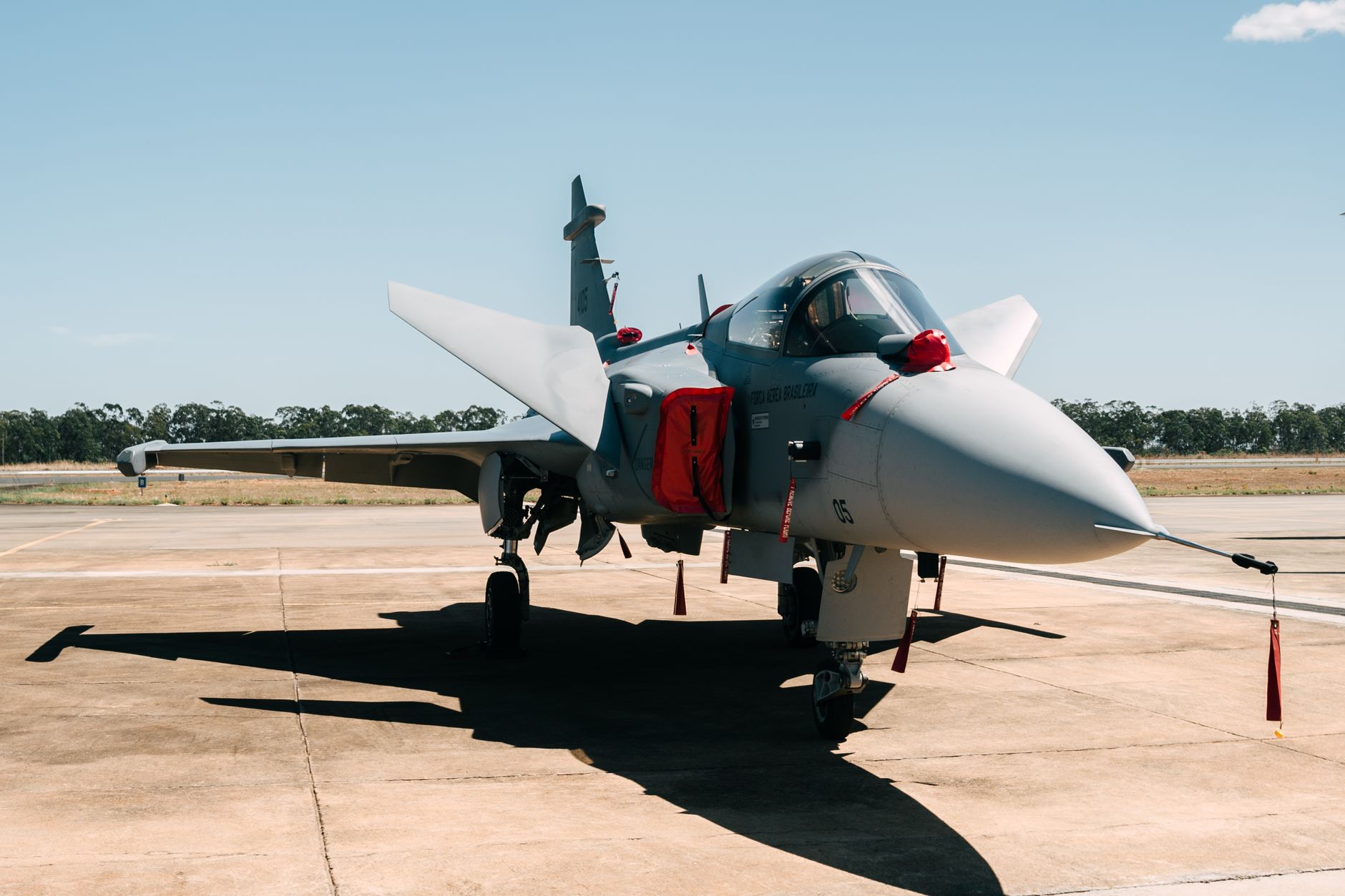 a Rafale multirole fighter jet on a flight line at a French air base, ground support equipment positioned nearby, overcast sky