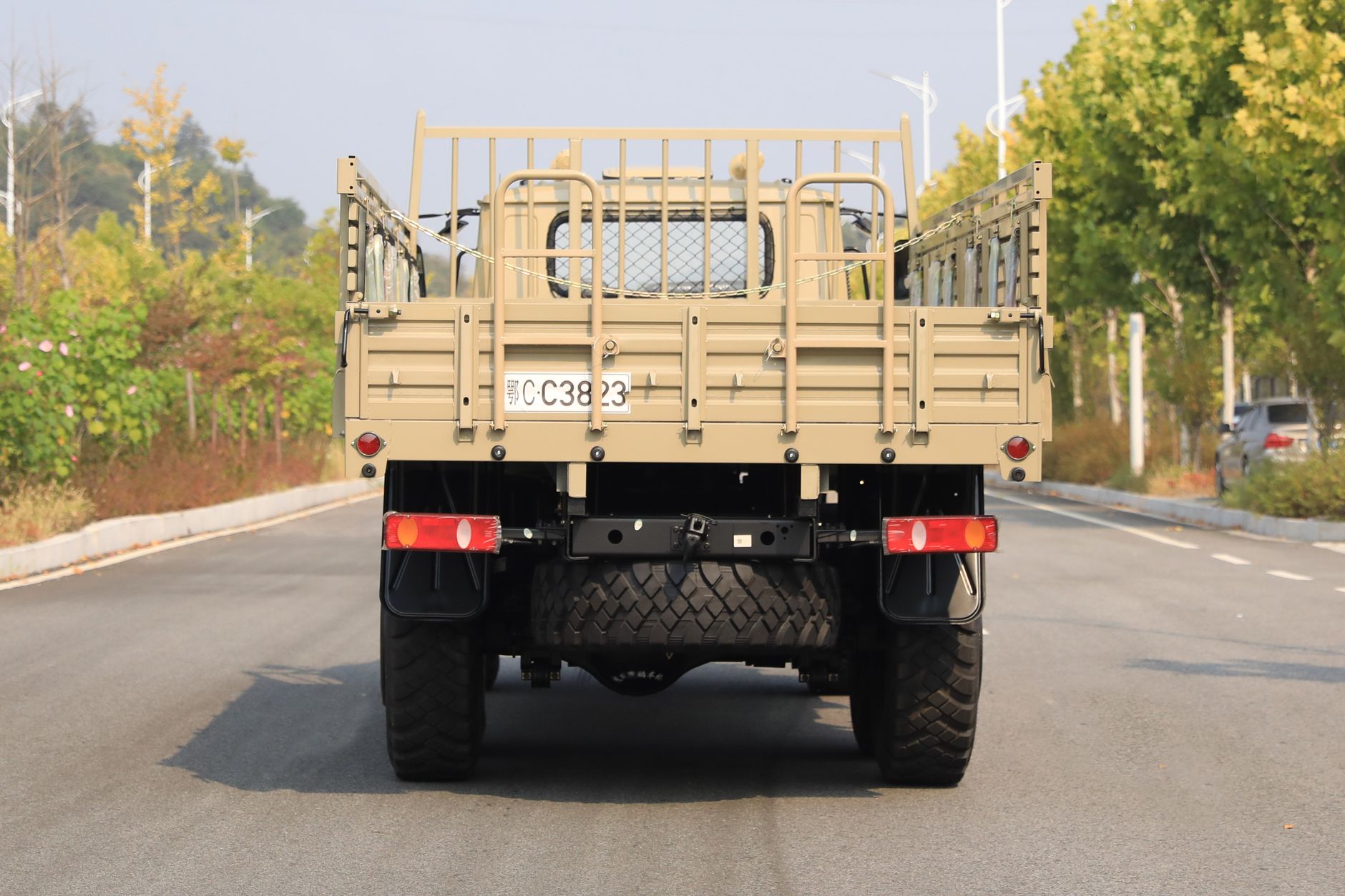 close-up of a light tactical vehicle chassis showing a modular rear cargo deck and roll-bar framework in an indoor exhibition hall with neutral industrial lighting