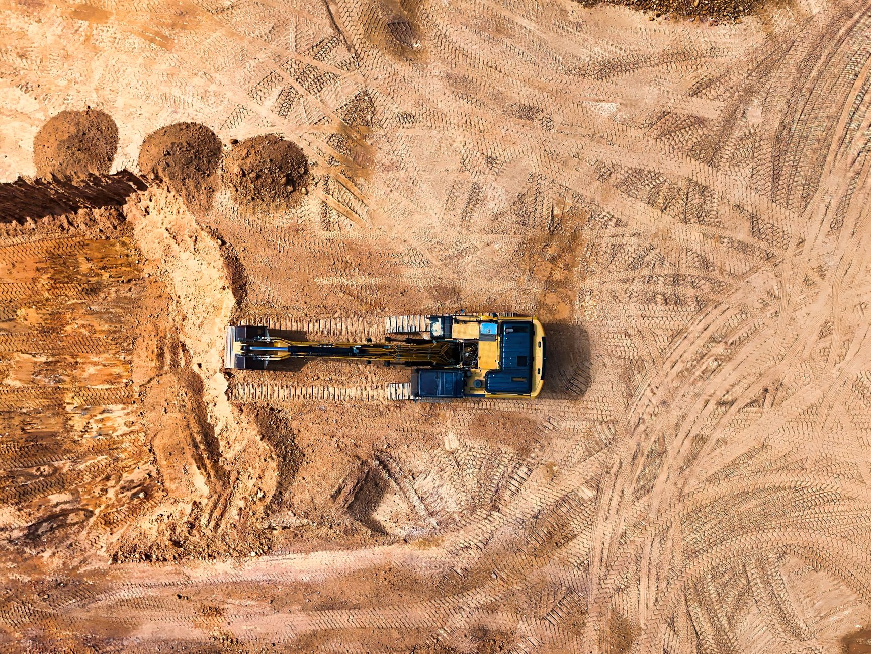 aerial view of a remote industrial construction site surrounded by arid terrain, with prefabricated structures and earthwork visible from above