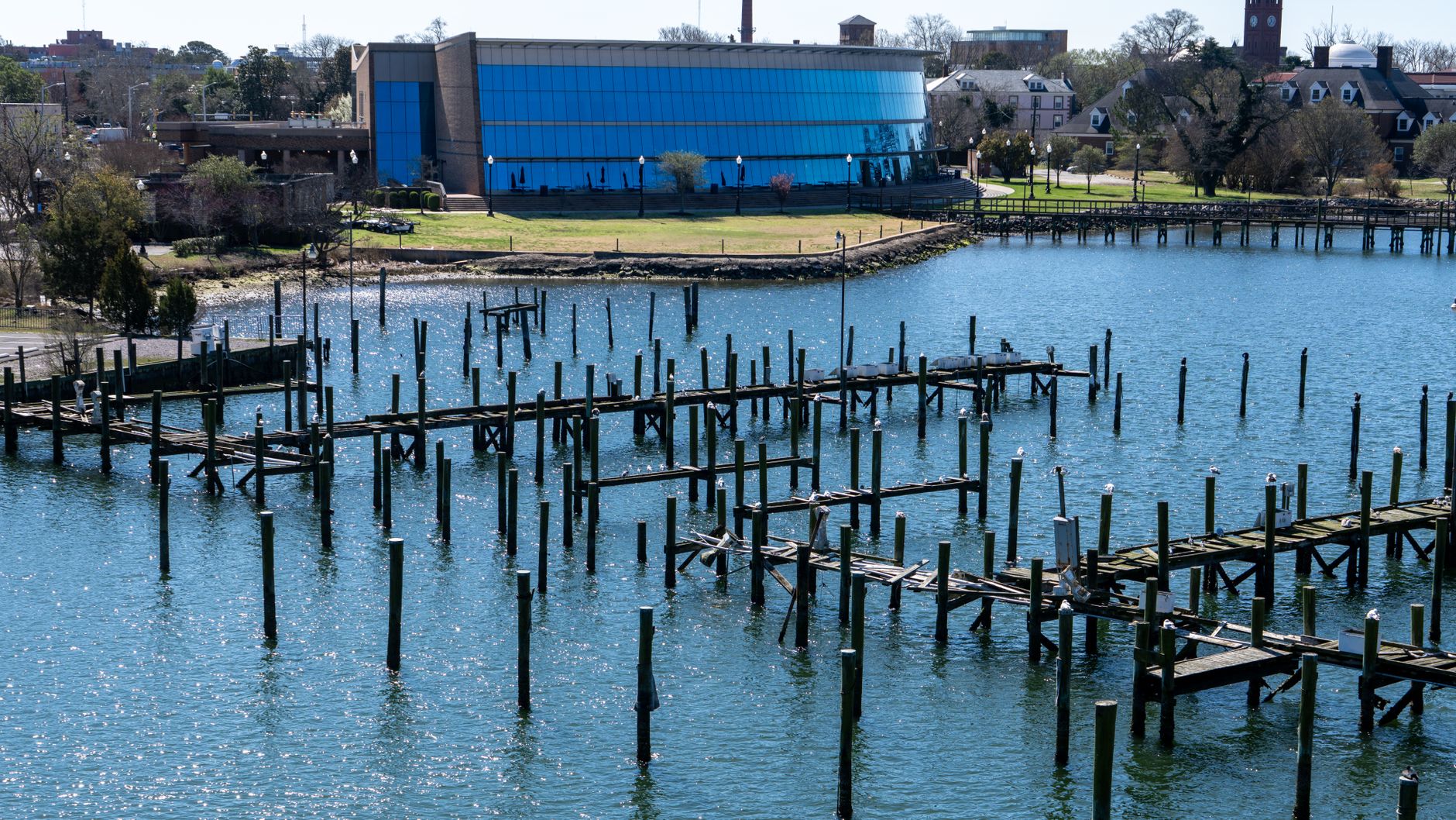 a naval research facility waterfront dock with a large unmanned underwater vehicle partially submerged during a test operation, open water visible in the background