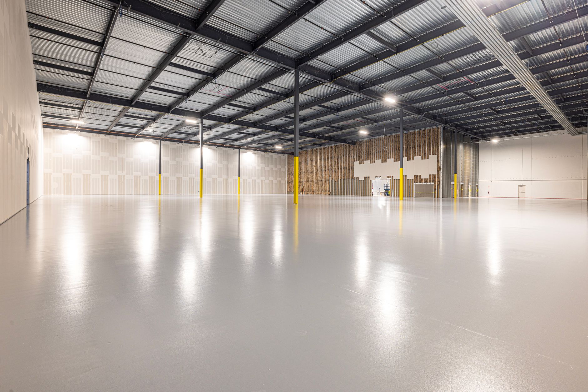an empty industrial warehouse interior with high ceilings and loading bay doors, representing a military equipment staging or storage facility